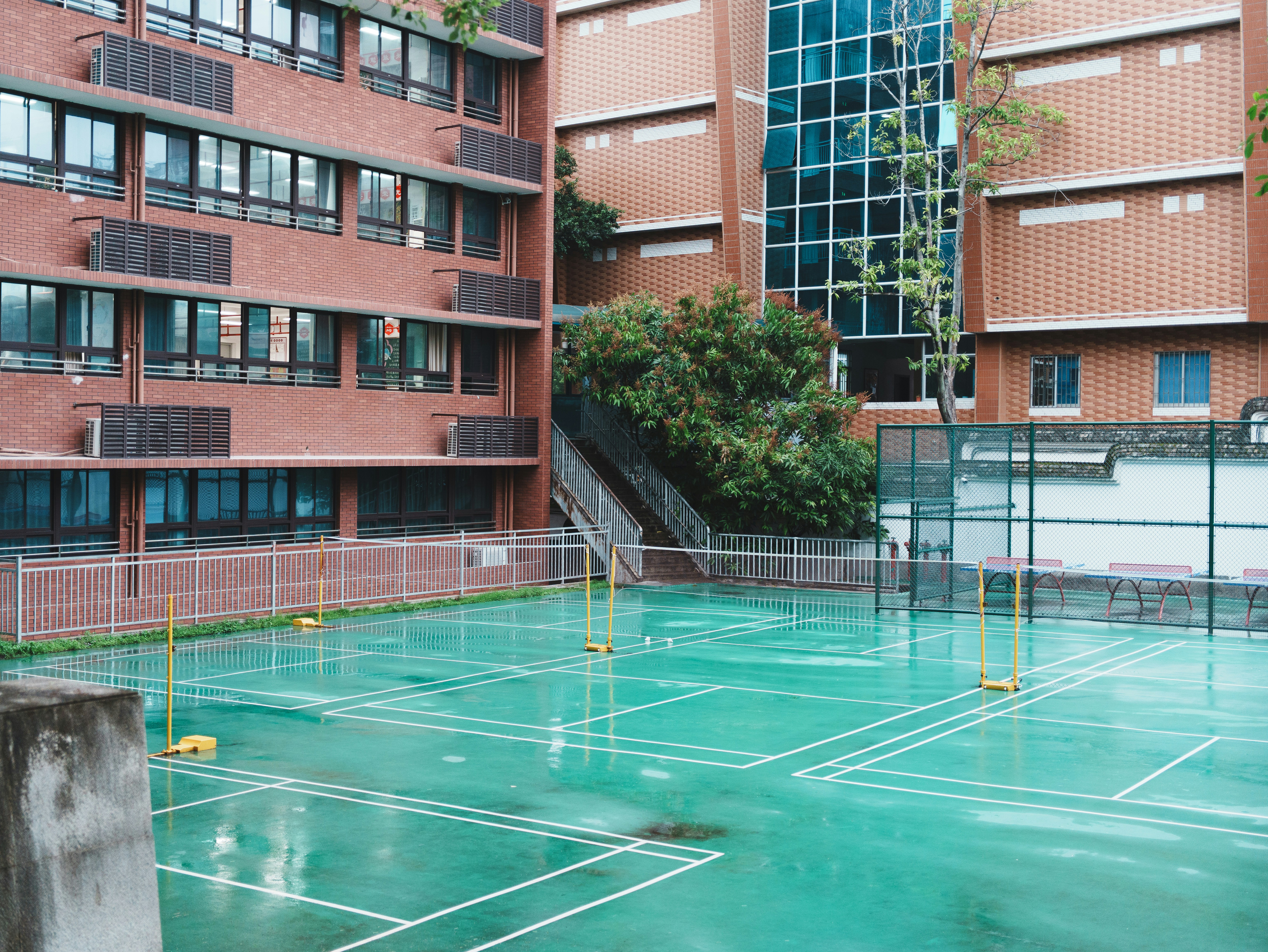 Courts de badminton extérieurs vides avec une surface verte humide.