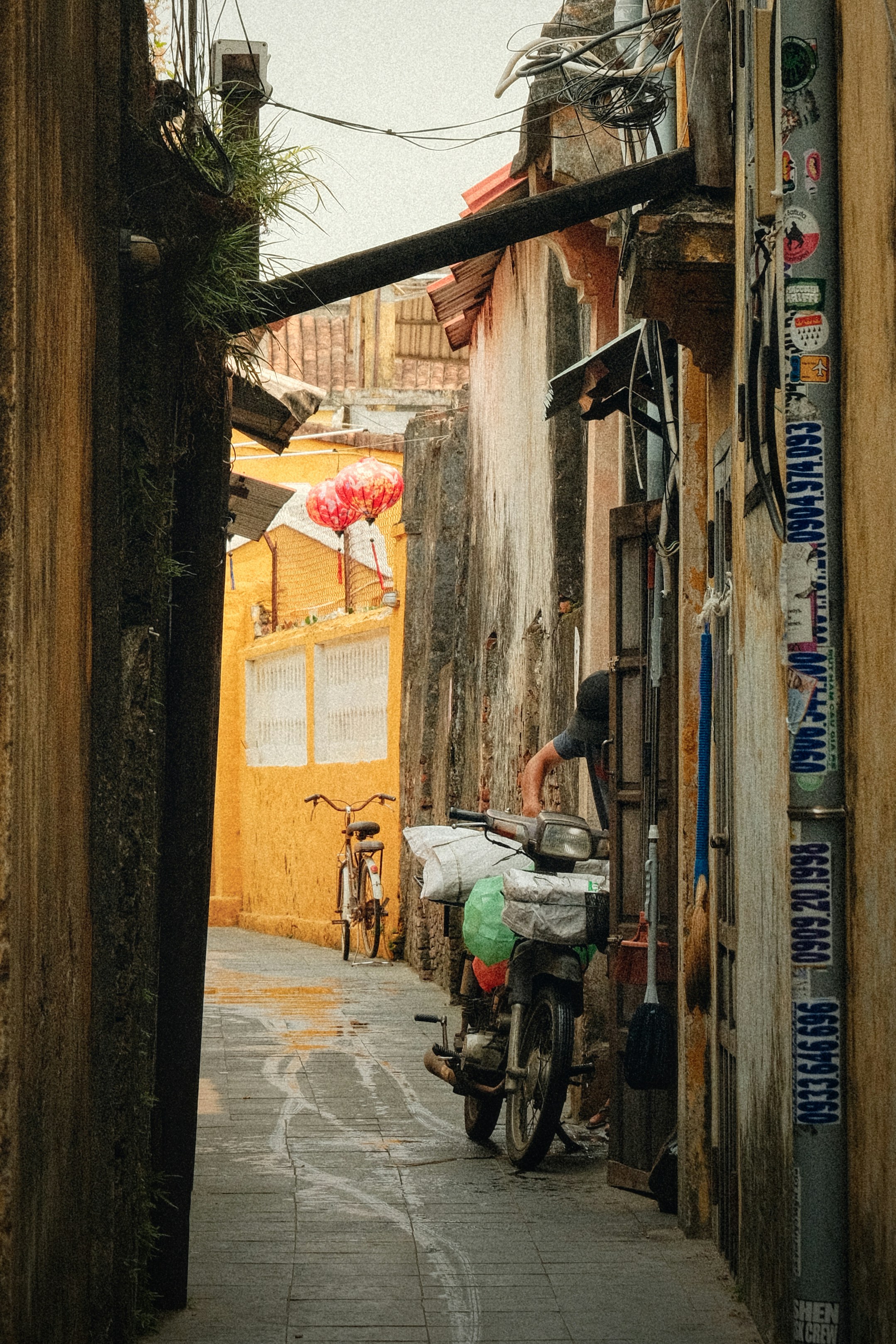 A narrow alleyway with a parked scooter and bicycle.