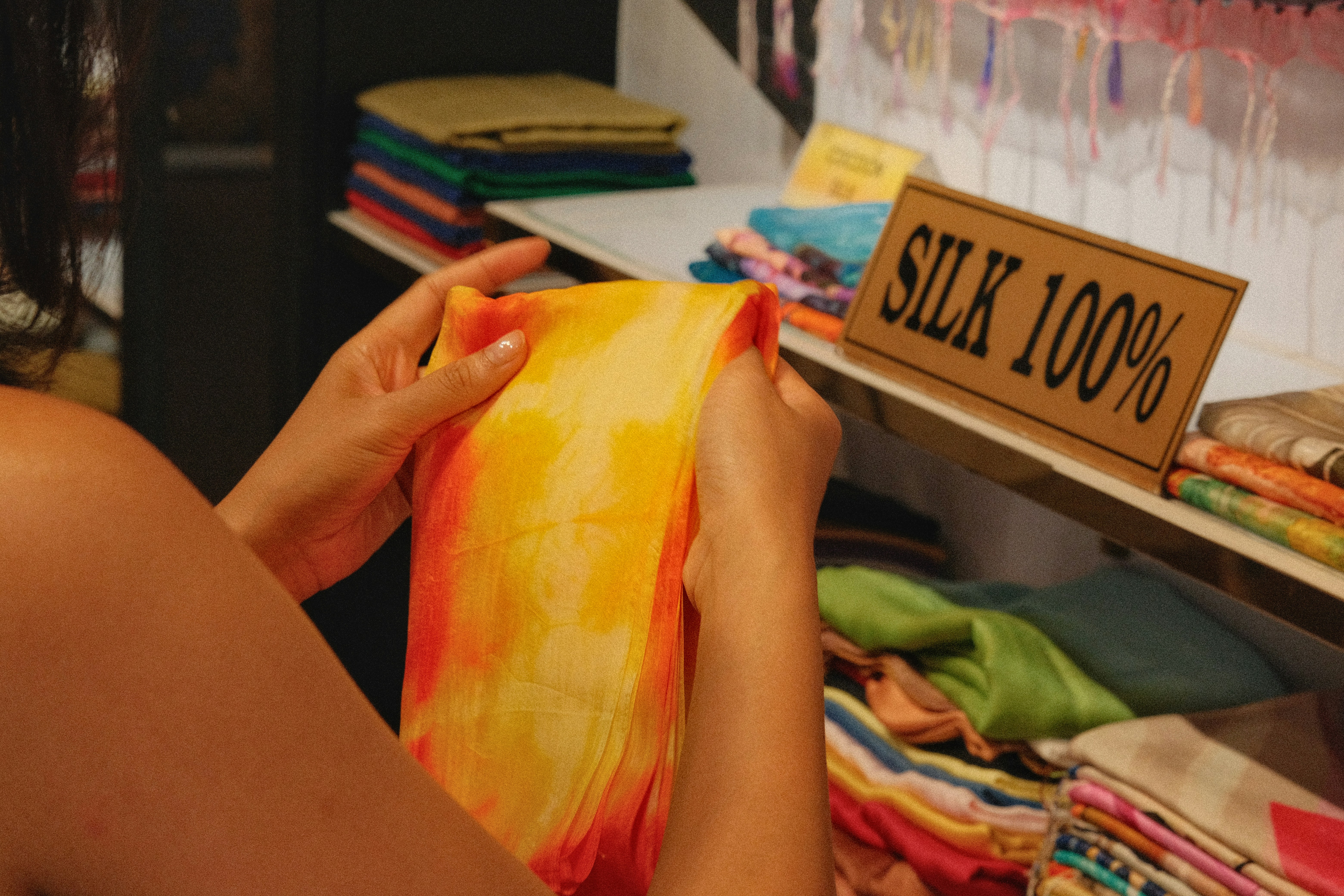 Woman examining colorful silk fabric in a store.