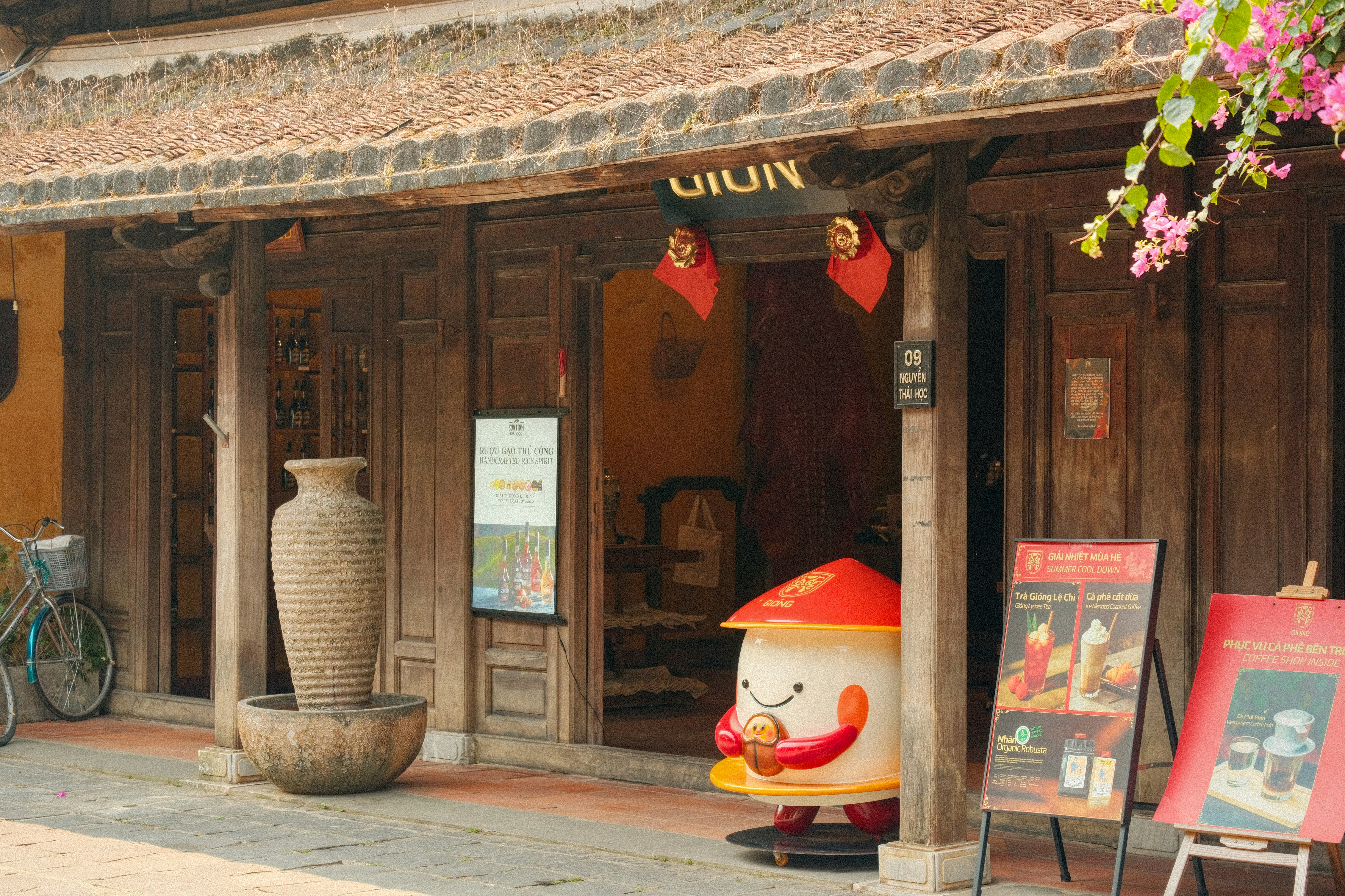 Traditional wooden building with vase, mascot, and signs.