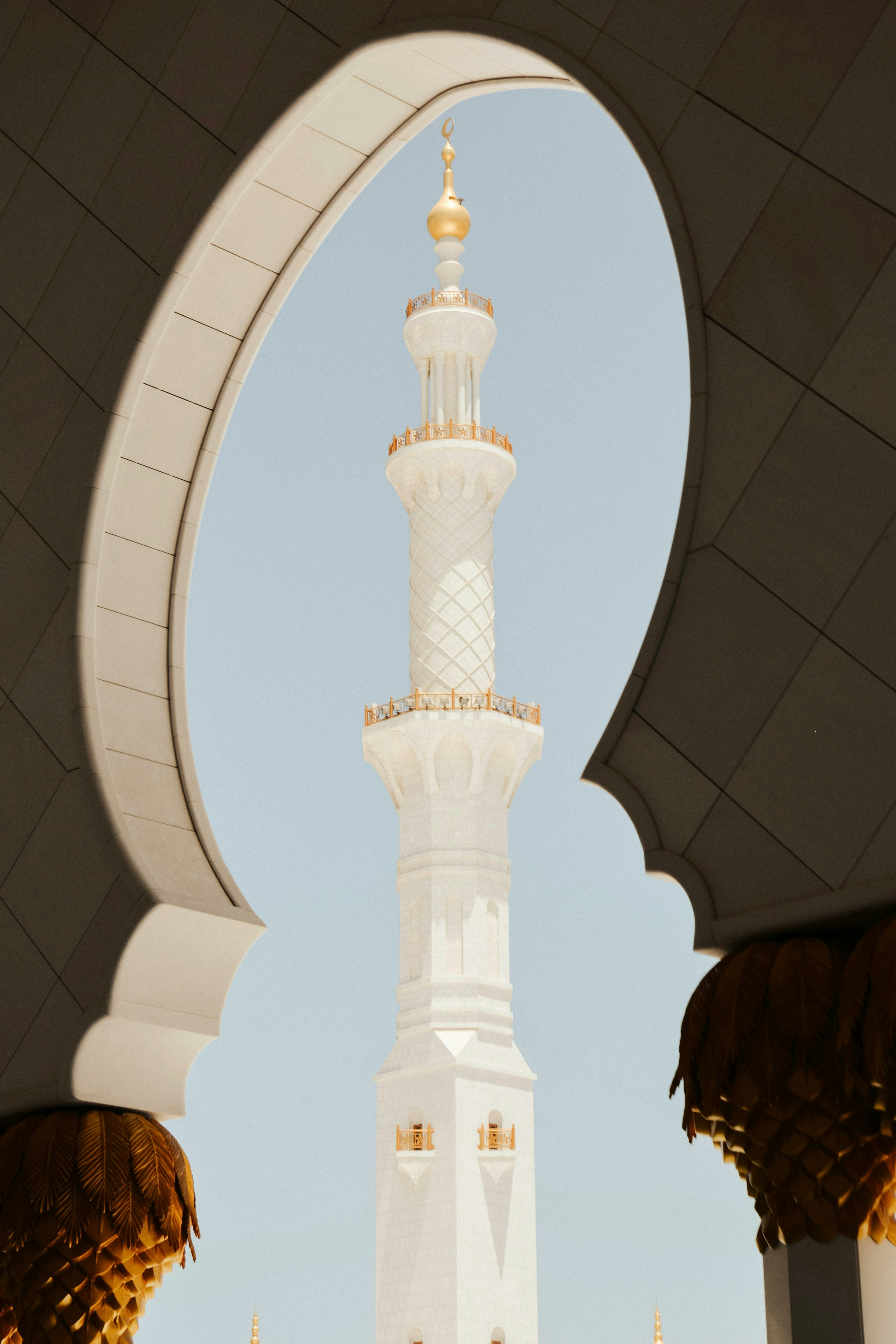 White minaret with golden details against blue sky