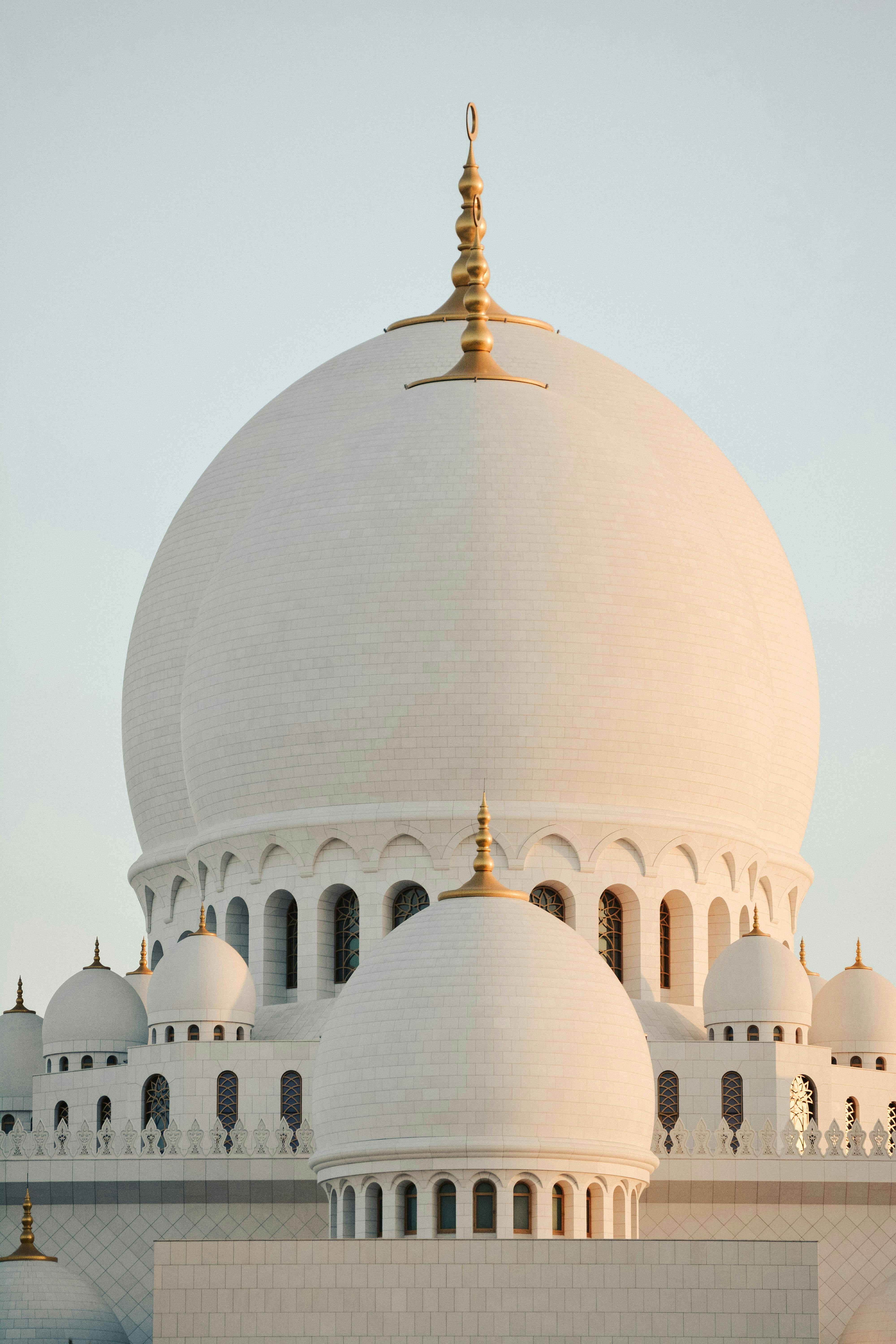 Grand white mosque domes with golden spires at dawn