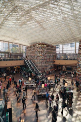 People browsing books in a large library with tall shelves.