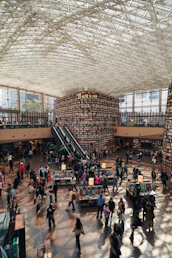 People browsing books in a large library with tall shelves.
