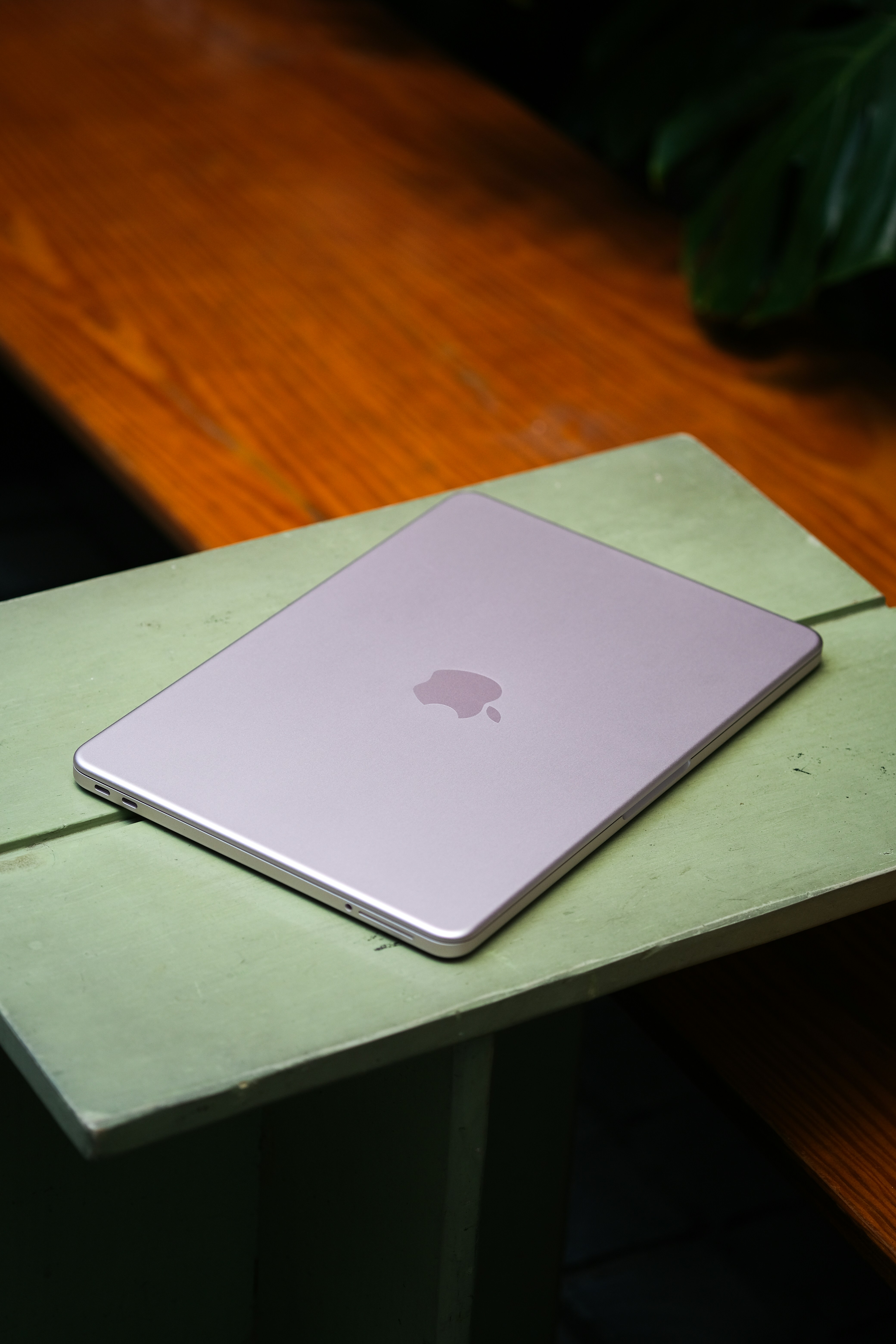 Um laptop rosa fechado repousa sobre uma superfície de madeira.