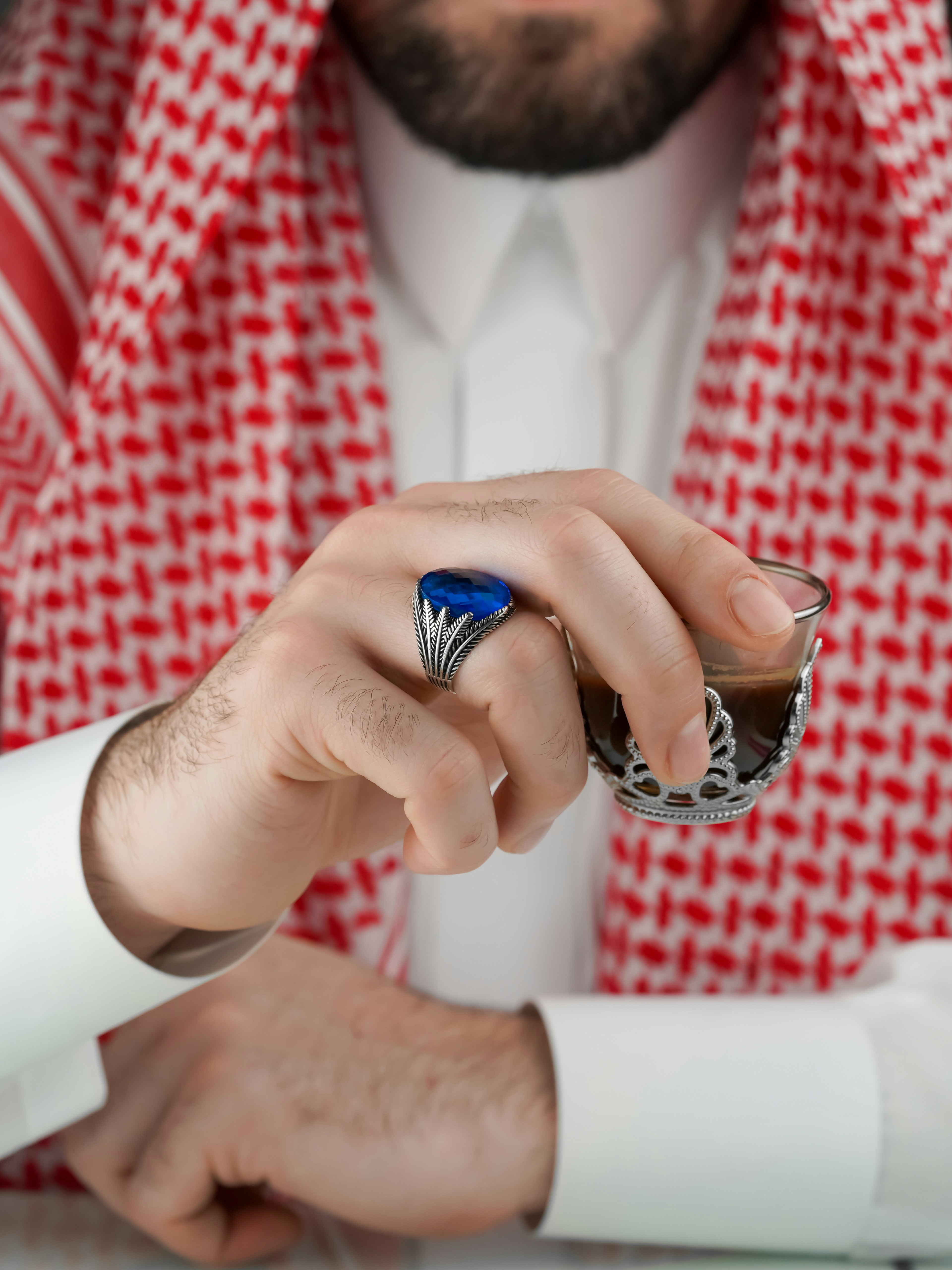 Hombre con traje tradicional saudí sosteniendo café
