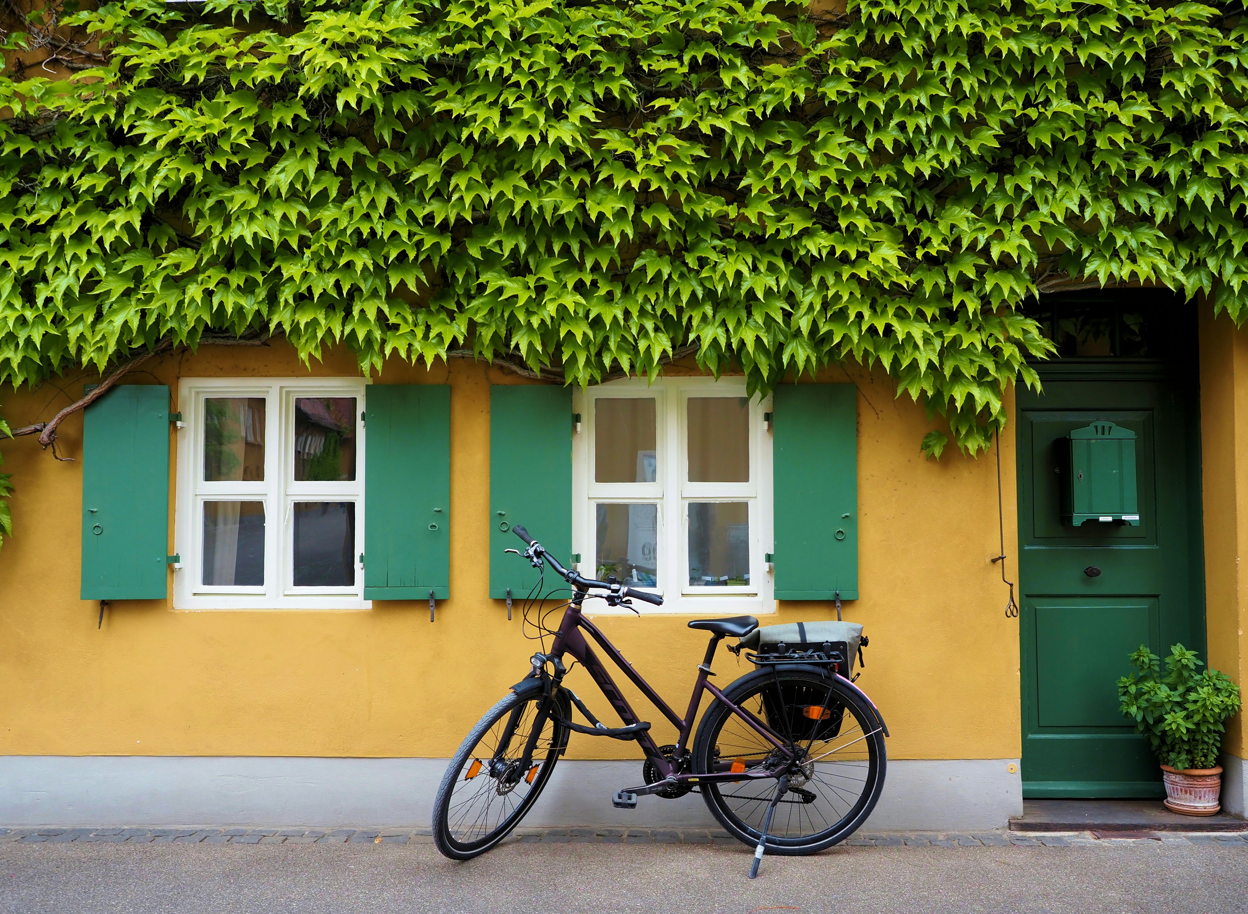 Bicycle parked outside a charming house with green shutters.