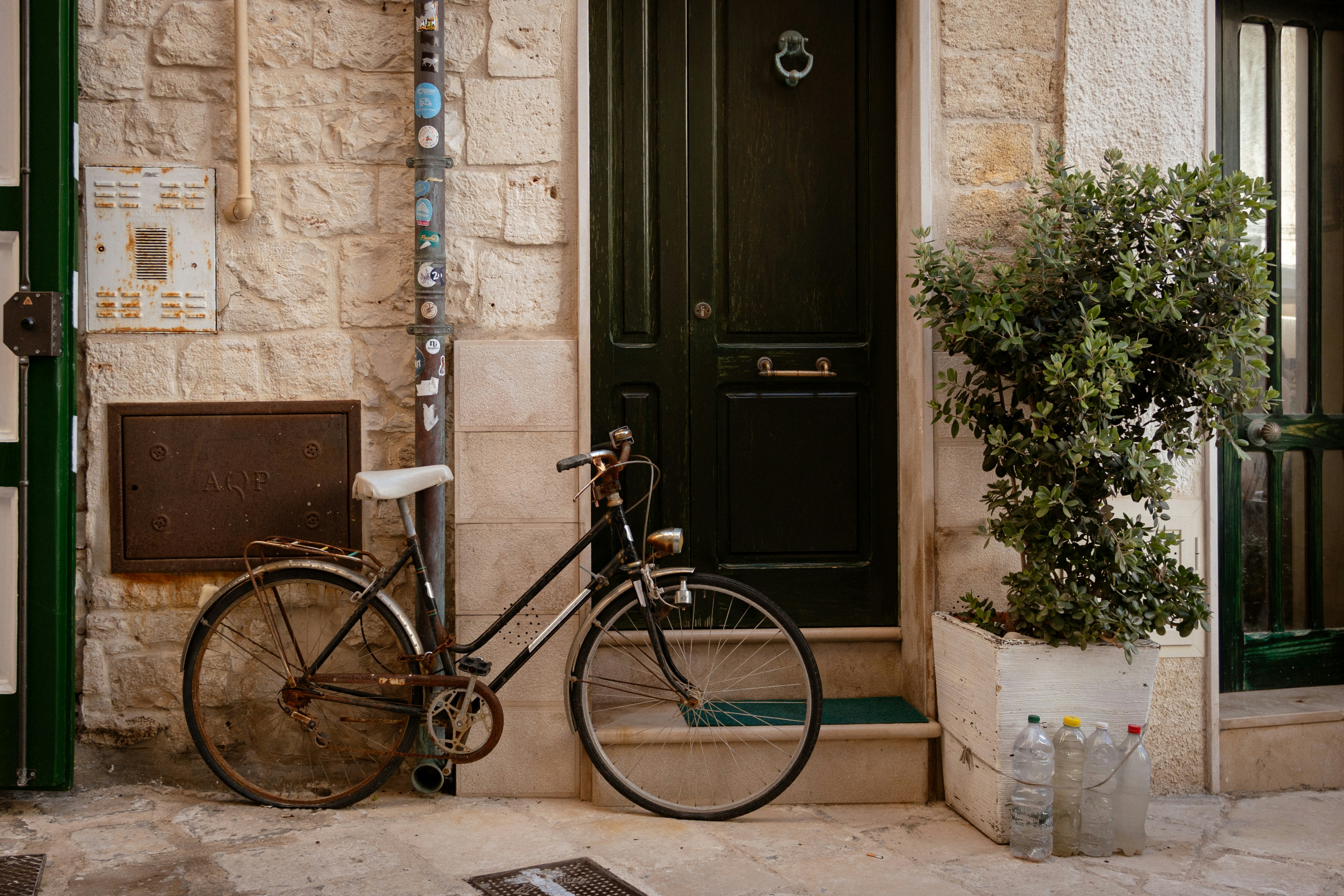 Bicicleta vintage aparcada junto a una puerta verde y un muro de piedra.