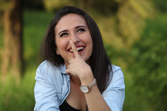 A young woman playfully touching her nose outdoors.