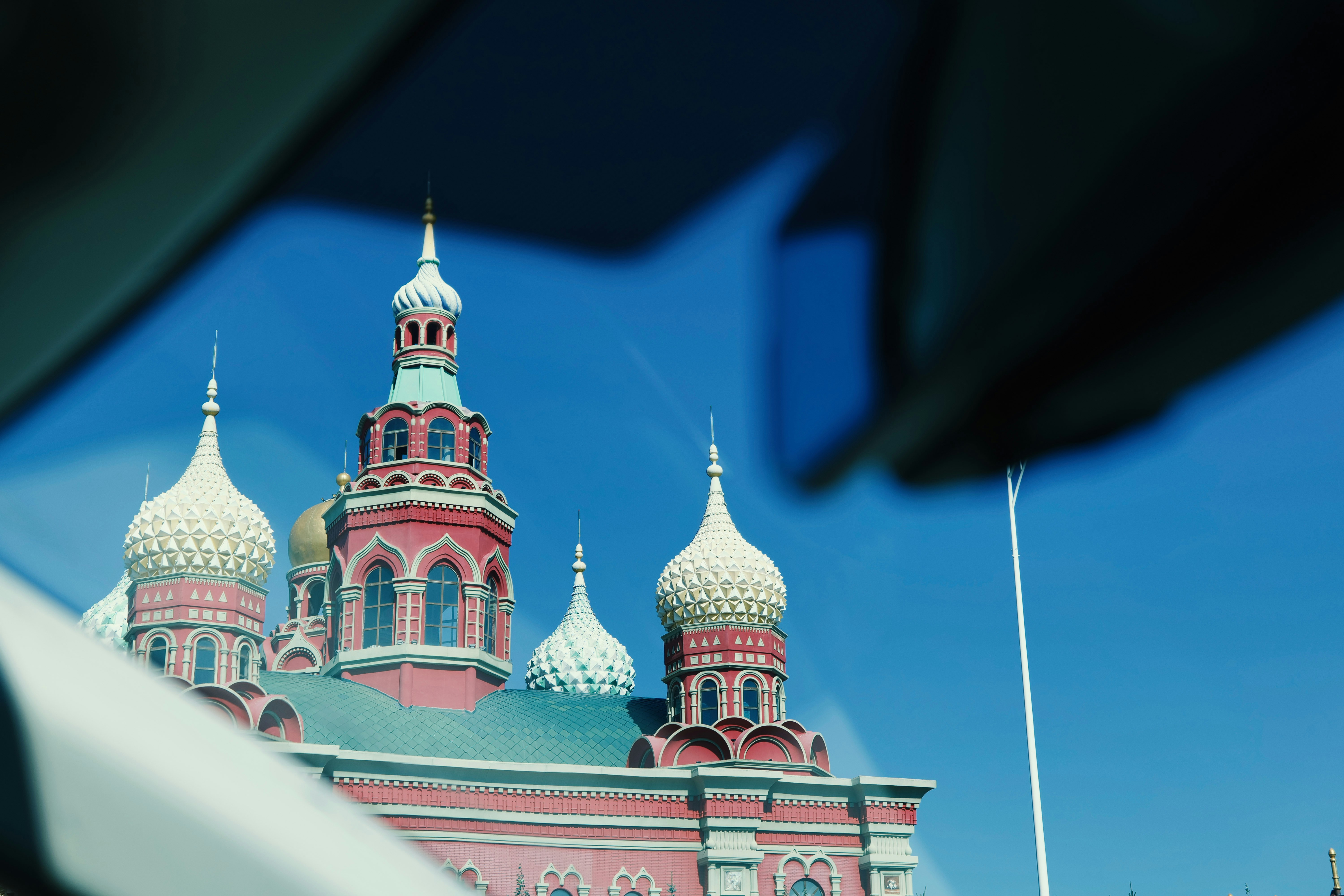Ornate red cathedral with domes against a bright blue sky