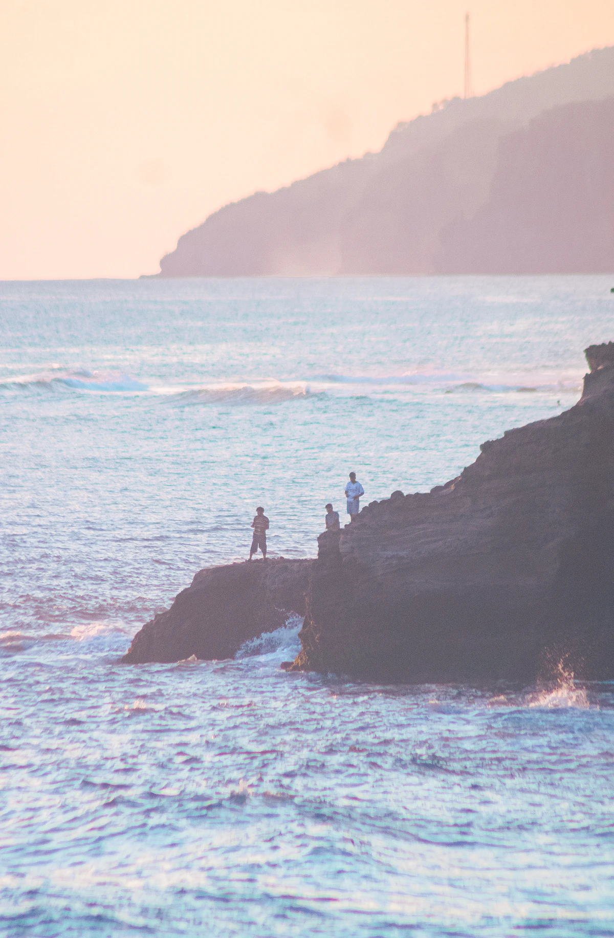 People fishing from the rocks at sunset