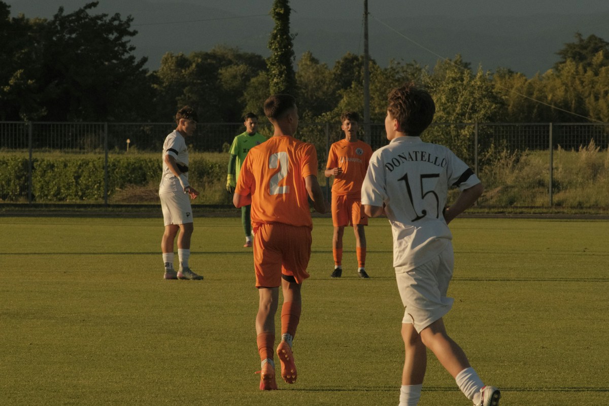 Young soccer players practicing on a grassy field during a youth sports camp.