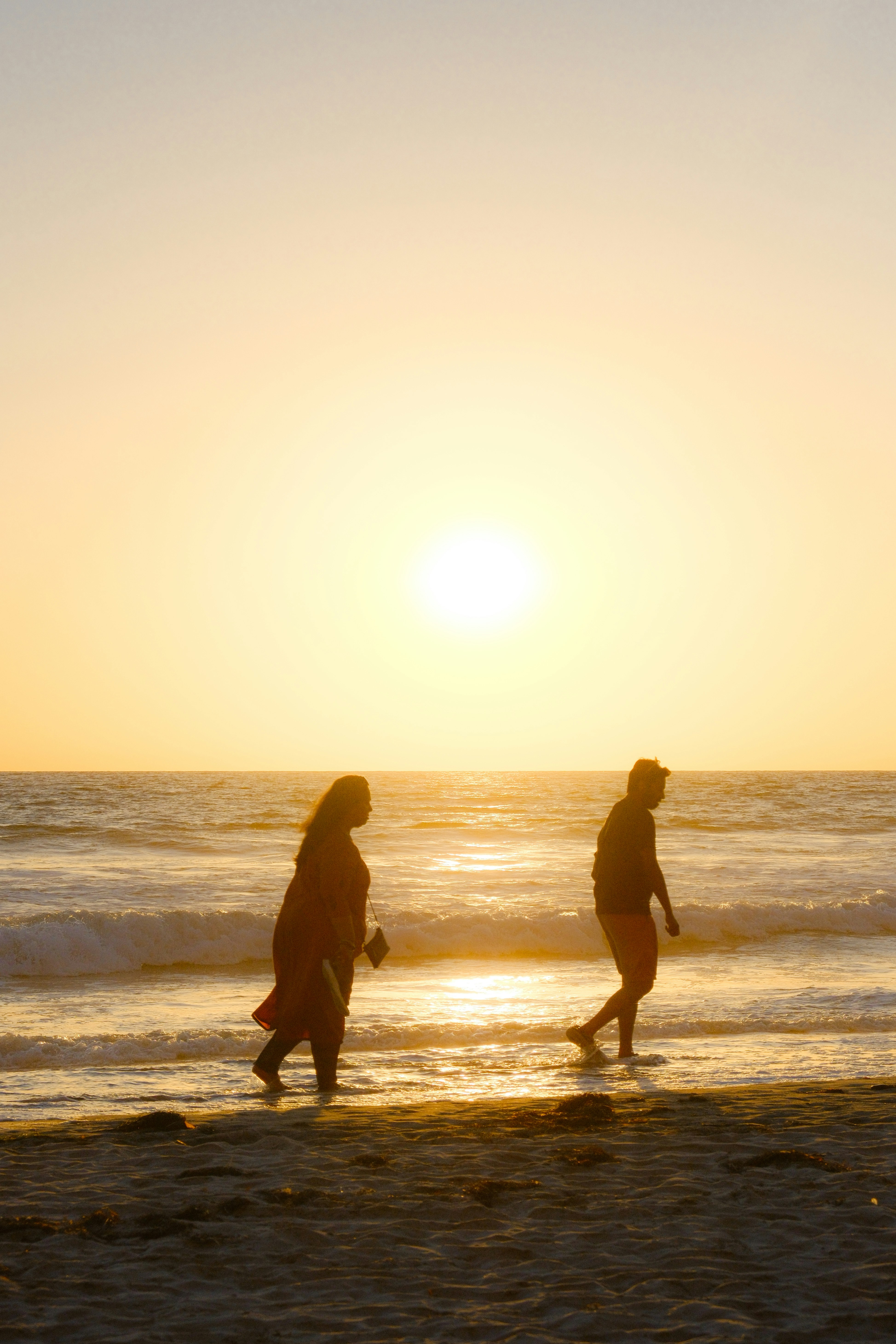 Zwei Personen gehen bei Sonnenuntergang am Strand entlang