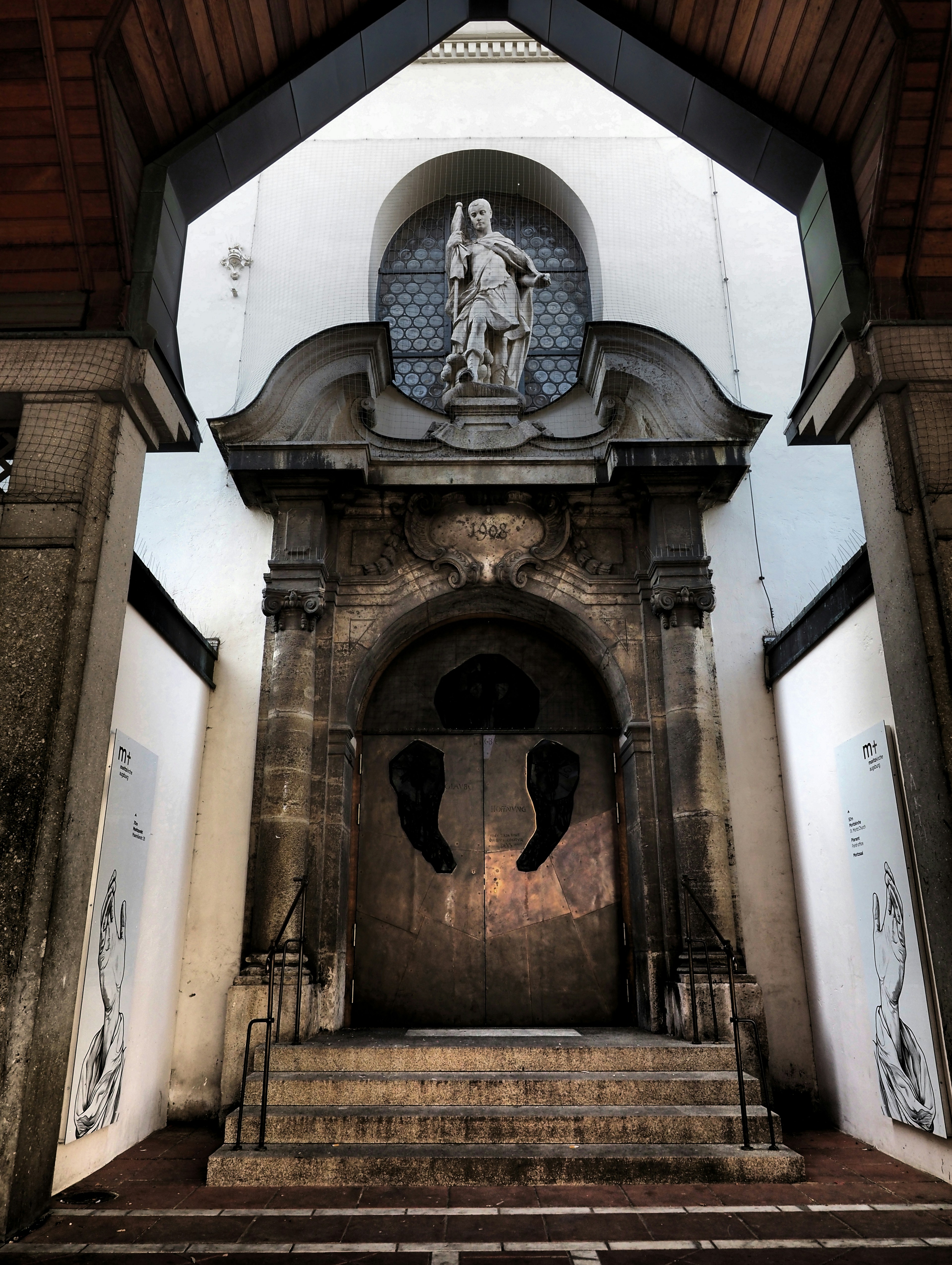 Ornate church entrance with a statue and dark, decorative doors.