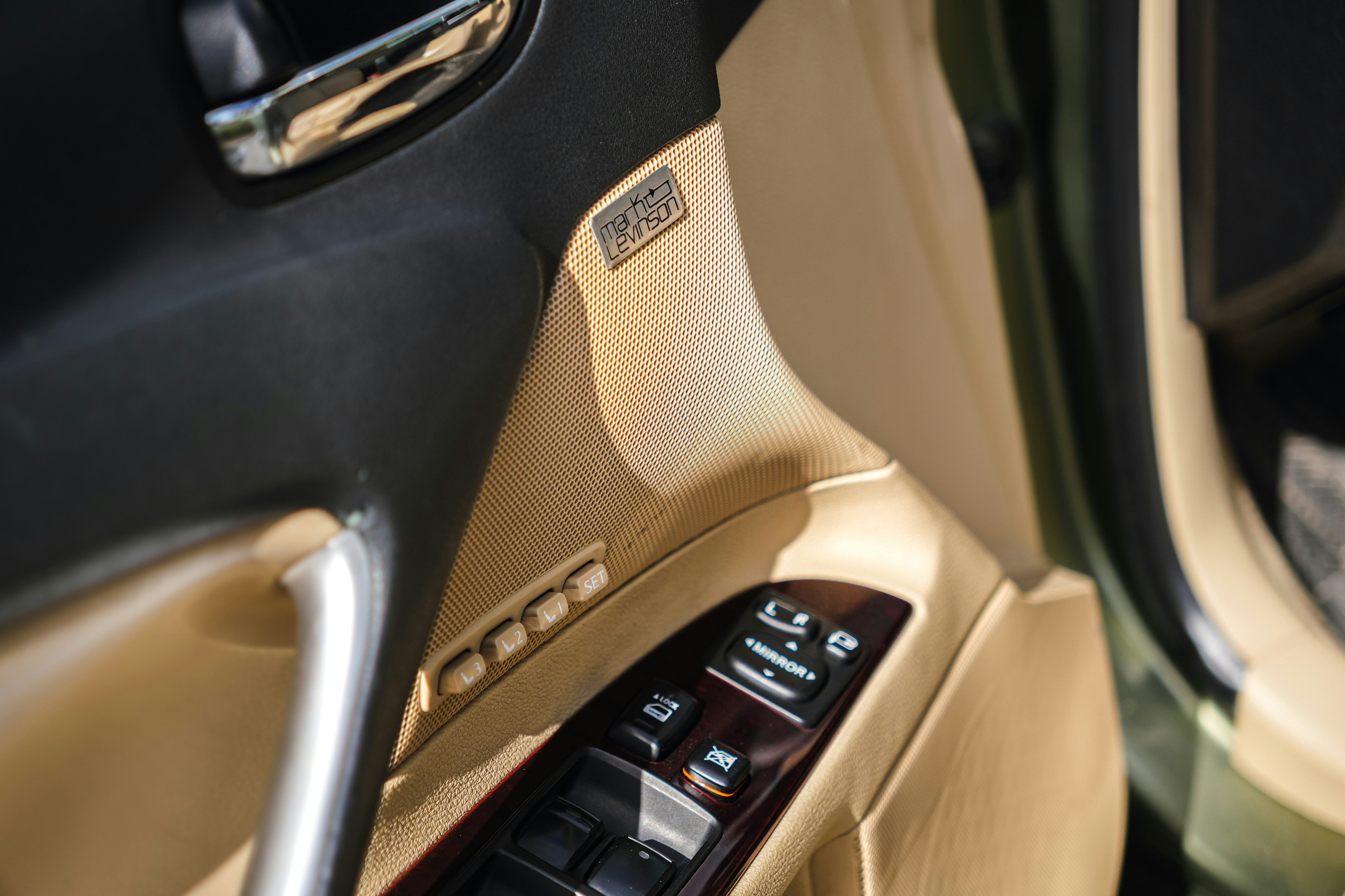 Car door interior with window controls and tan panel.