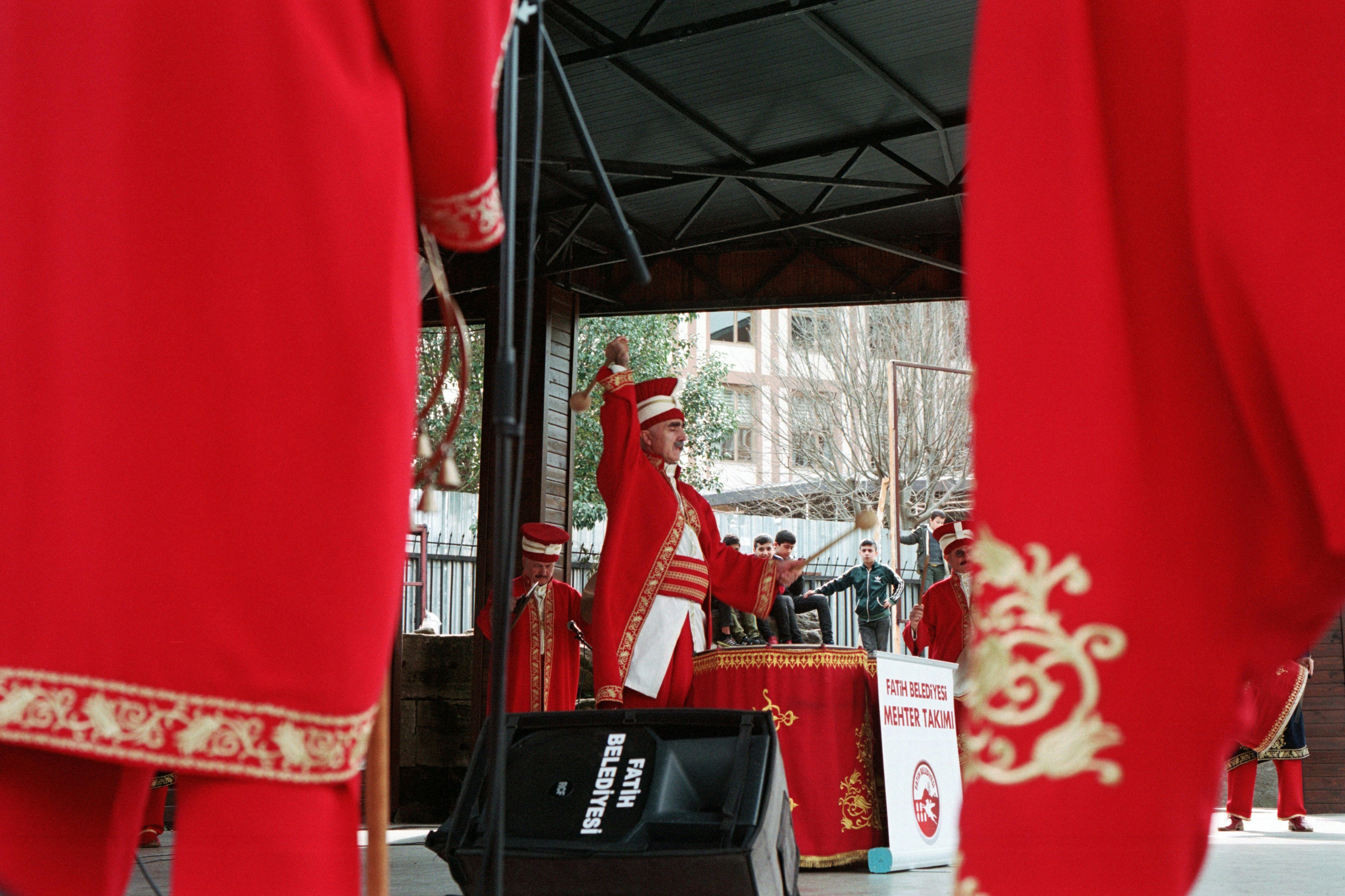 Performers in red costumes playing drums on stage. (Photo by ONUR KURT on Unsplash)