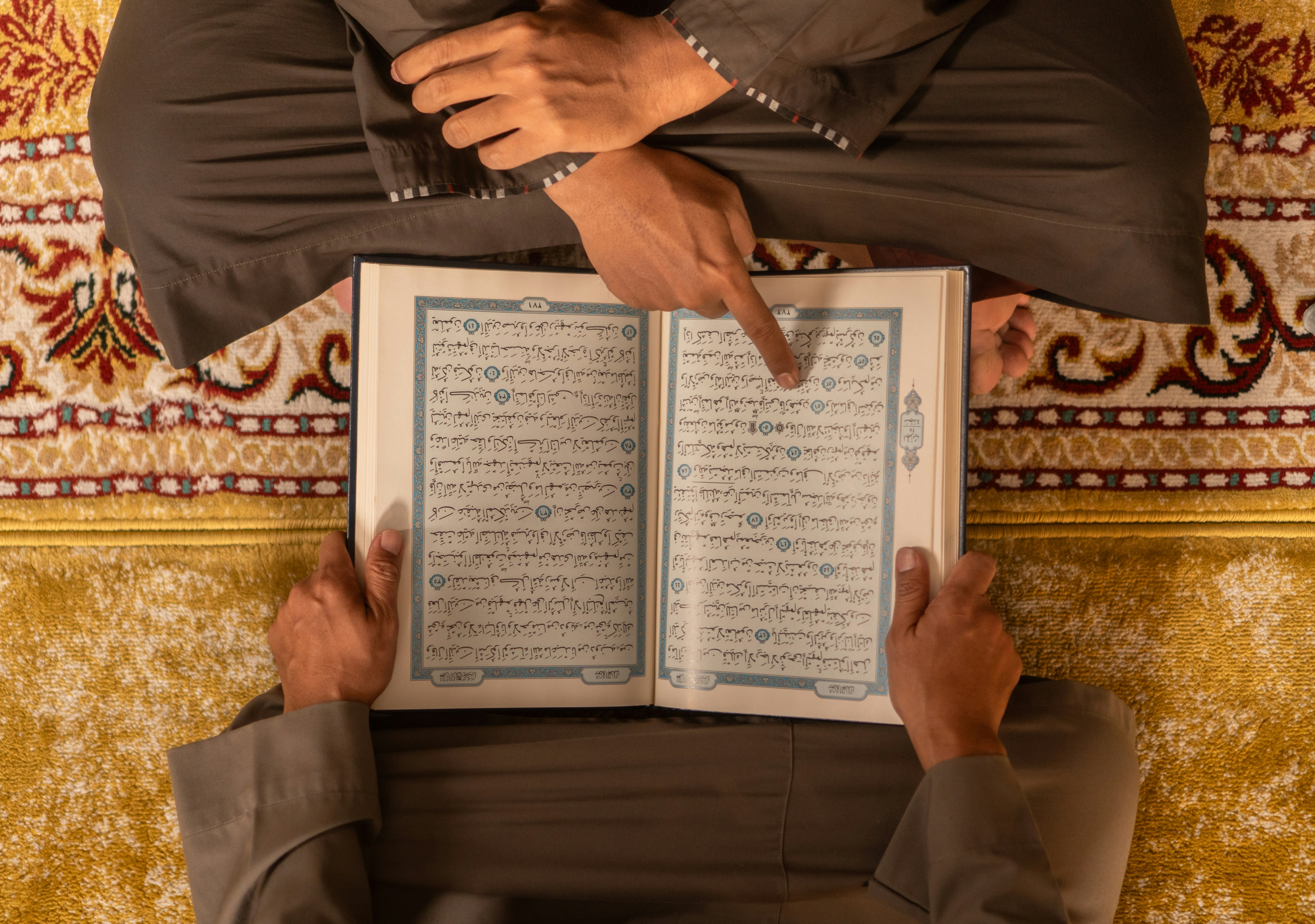Two people reading the quran together on a rug.