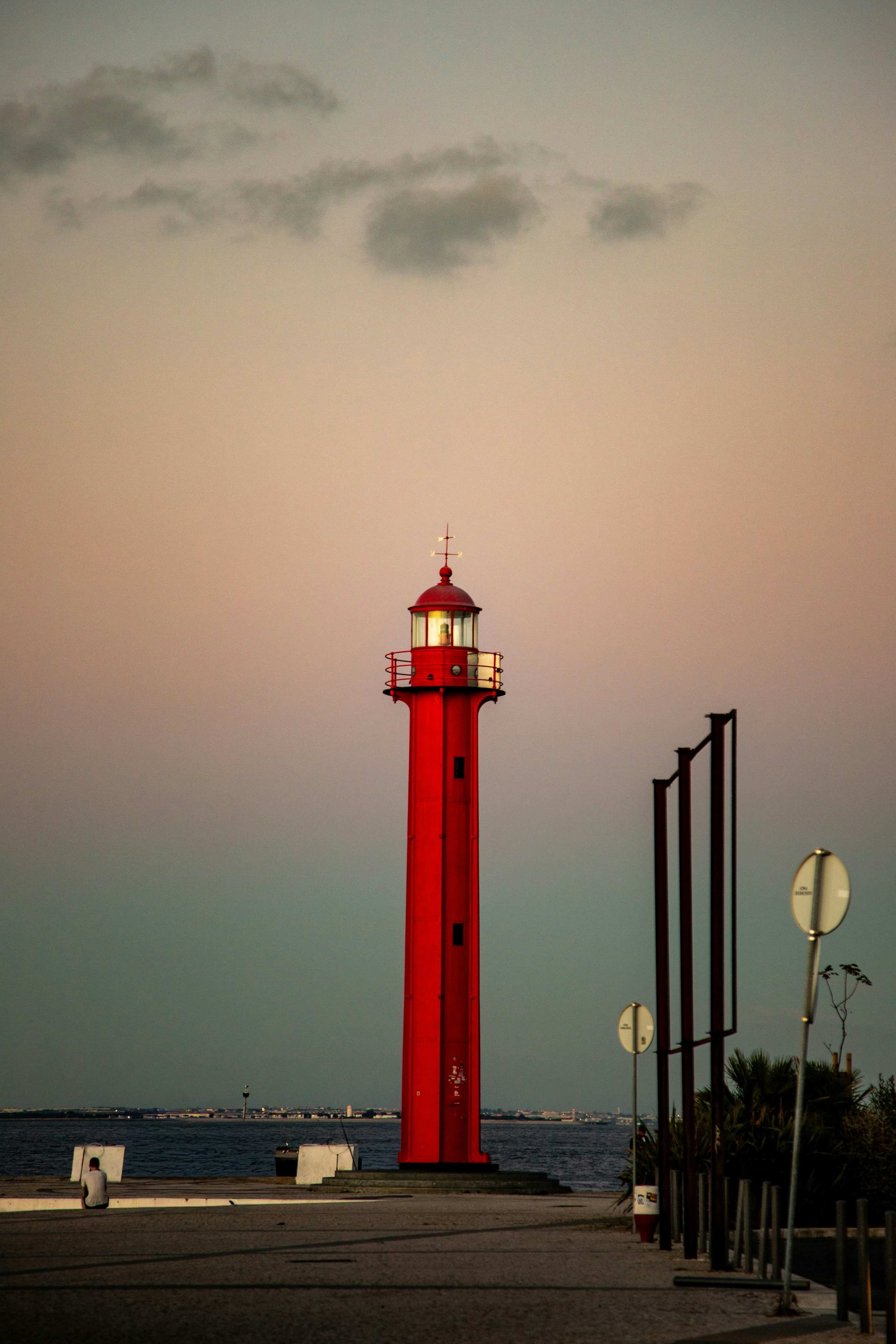 Mercusuar merah tinggi berdiri di langit pastel.