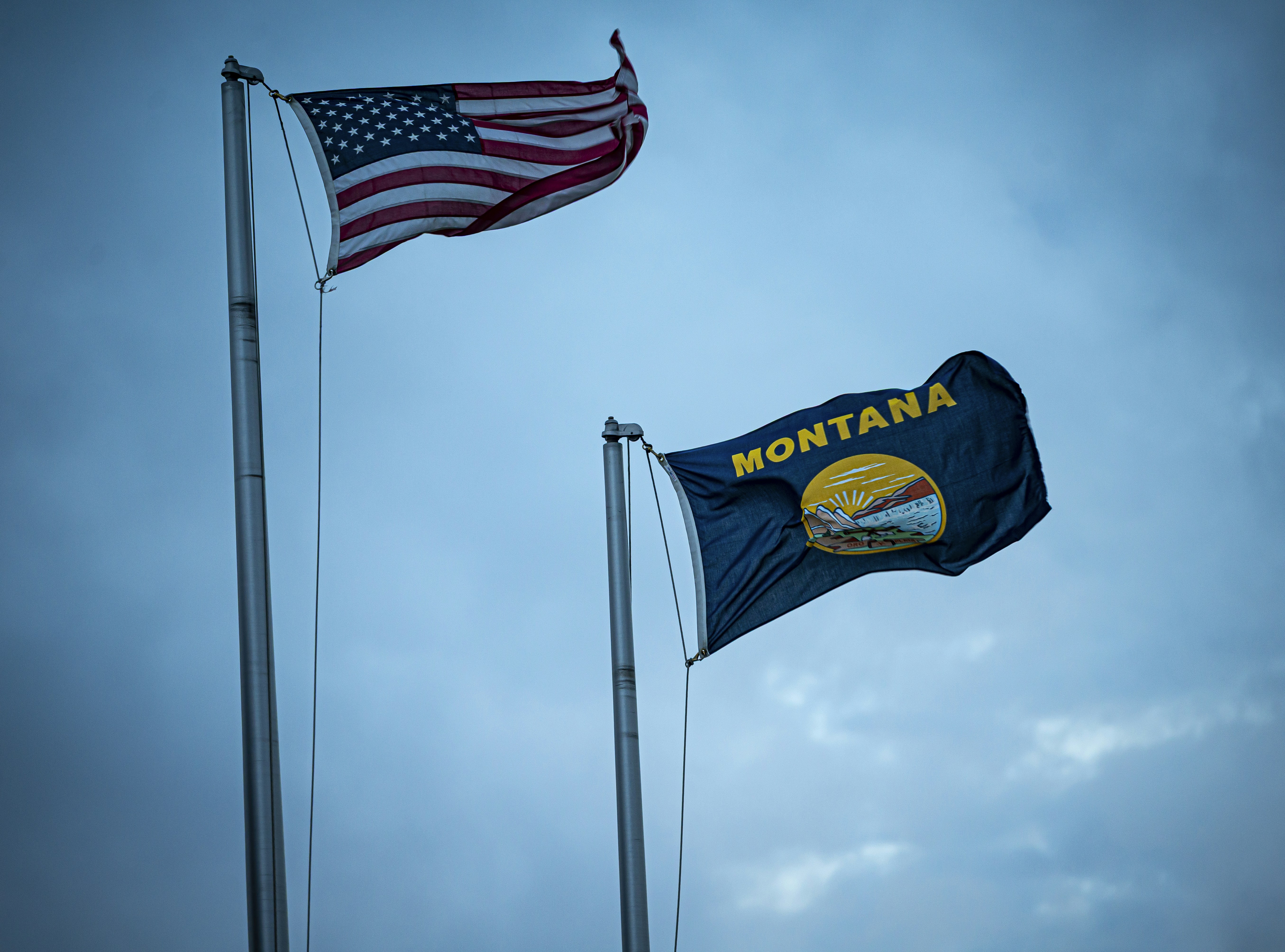 American and montana flags waving against a cloudy sky