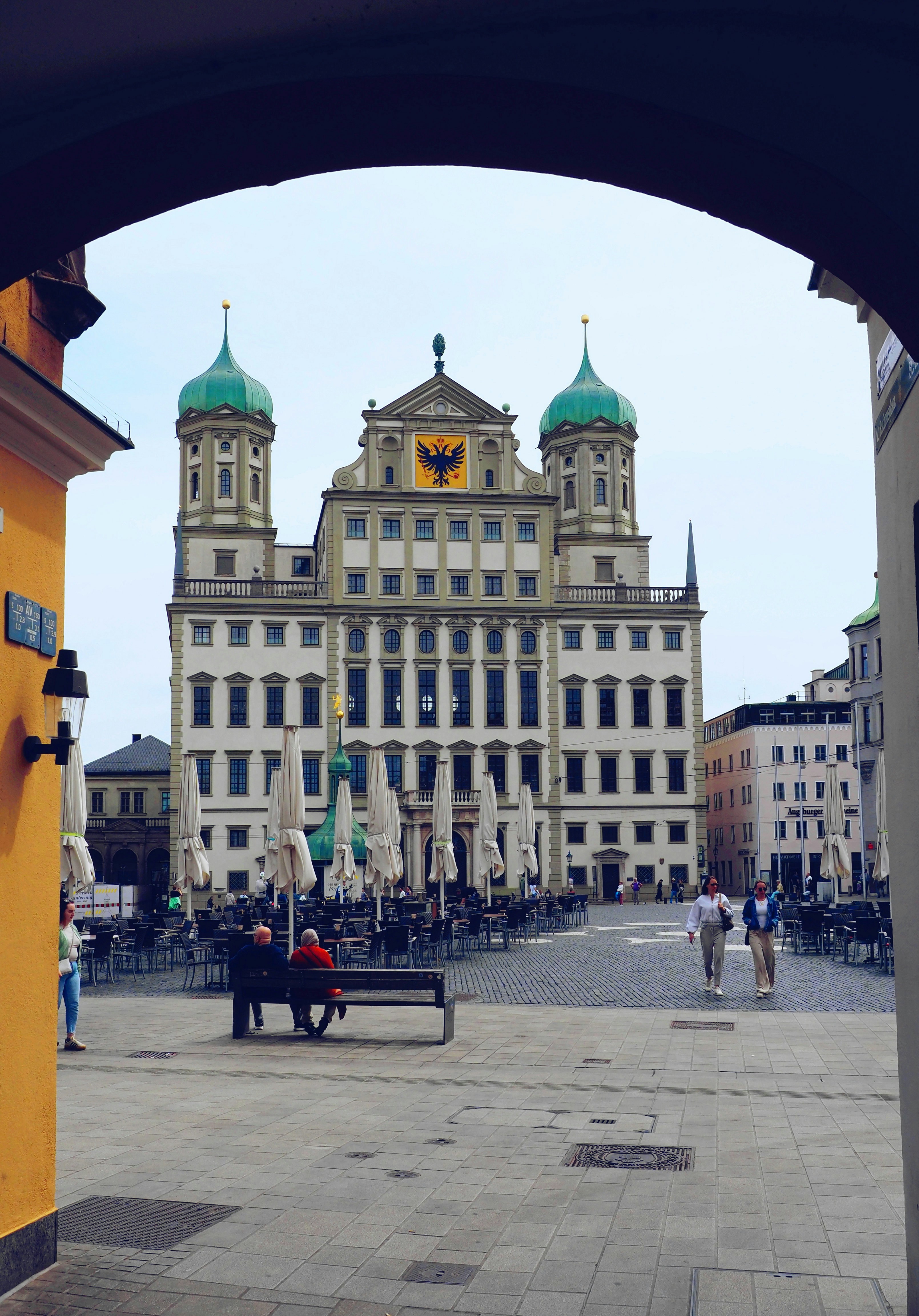 Historic building with green domes frames a european town square.