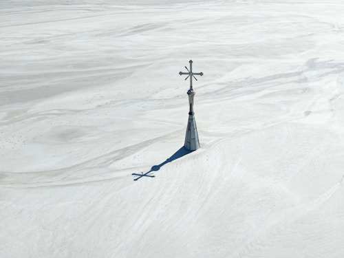A cross on a steeple casts a long shadow