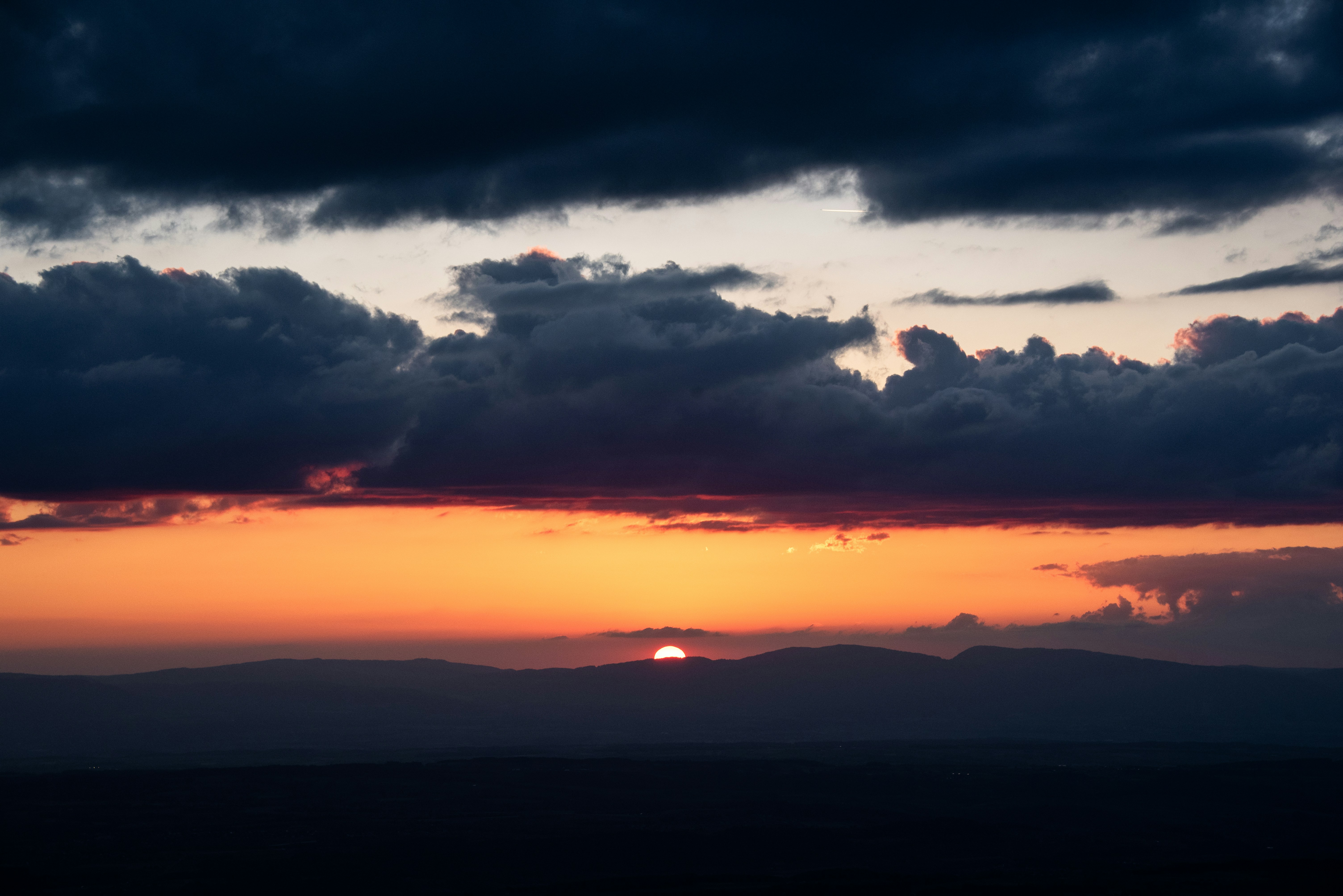 Sunset over dark mountains with dramatic clouds