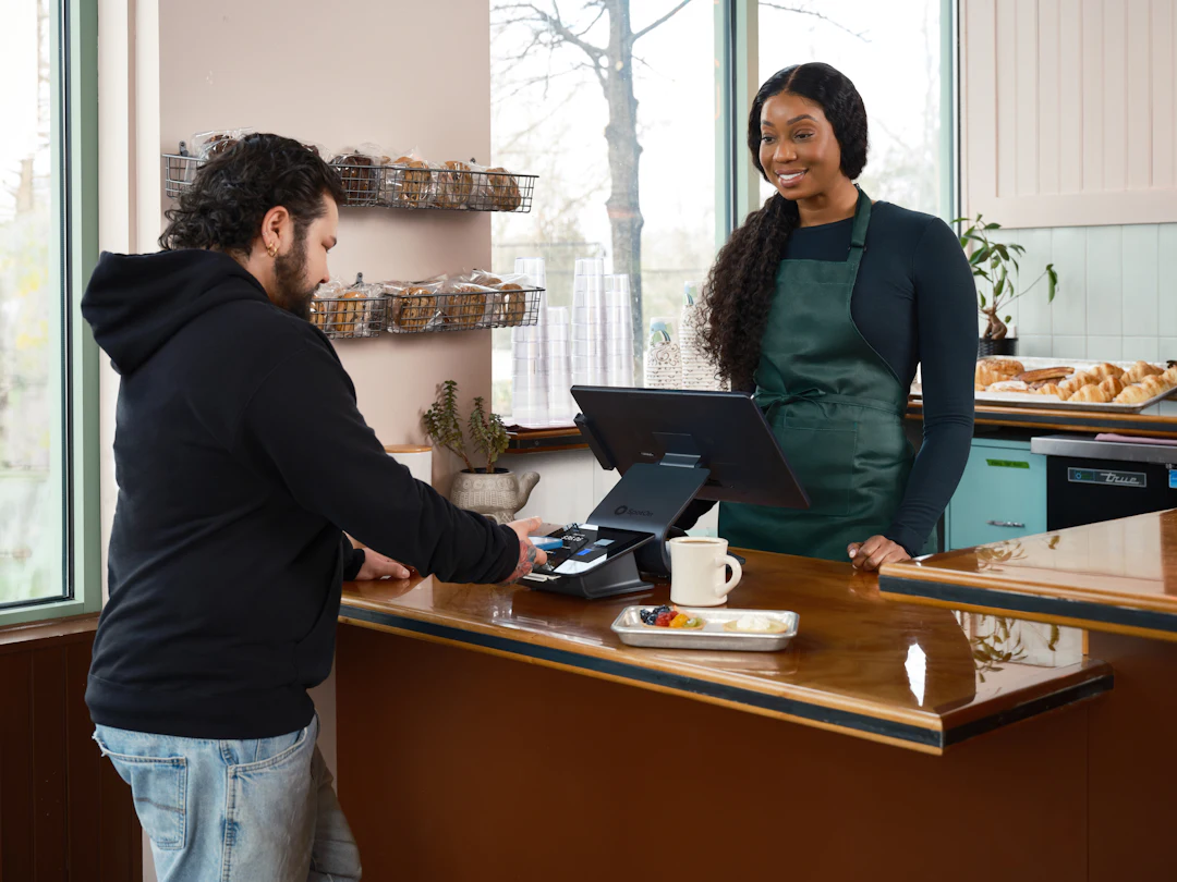 A customer paying a smiling owner at a café counter