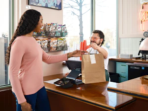 Customer receives a takeout bag from cashier.