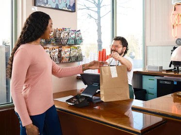 Customer receives a takeout bag from cashier.
