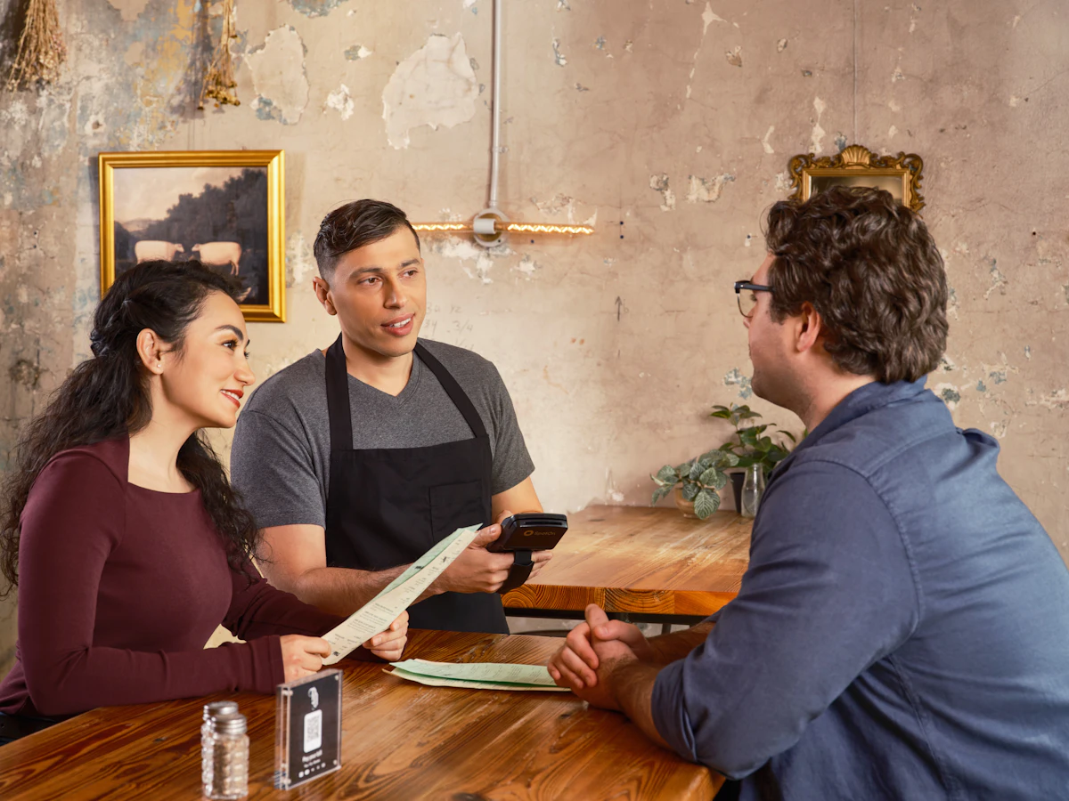 Serveur qui prend la commande de deux clients attablés