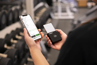 Person holding phone and payment device in gym