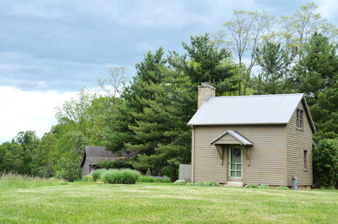 A small beige house with a metal roof.