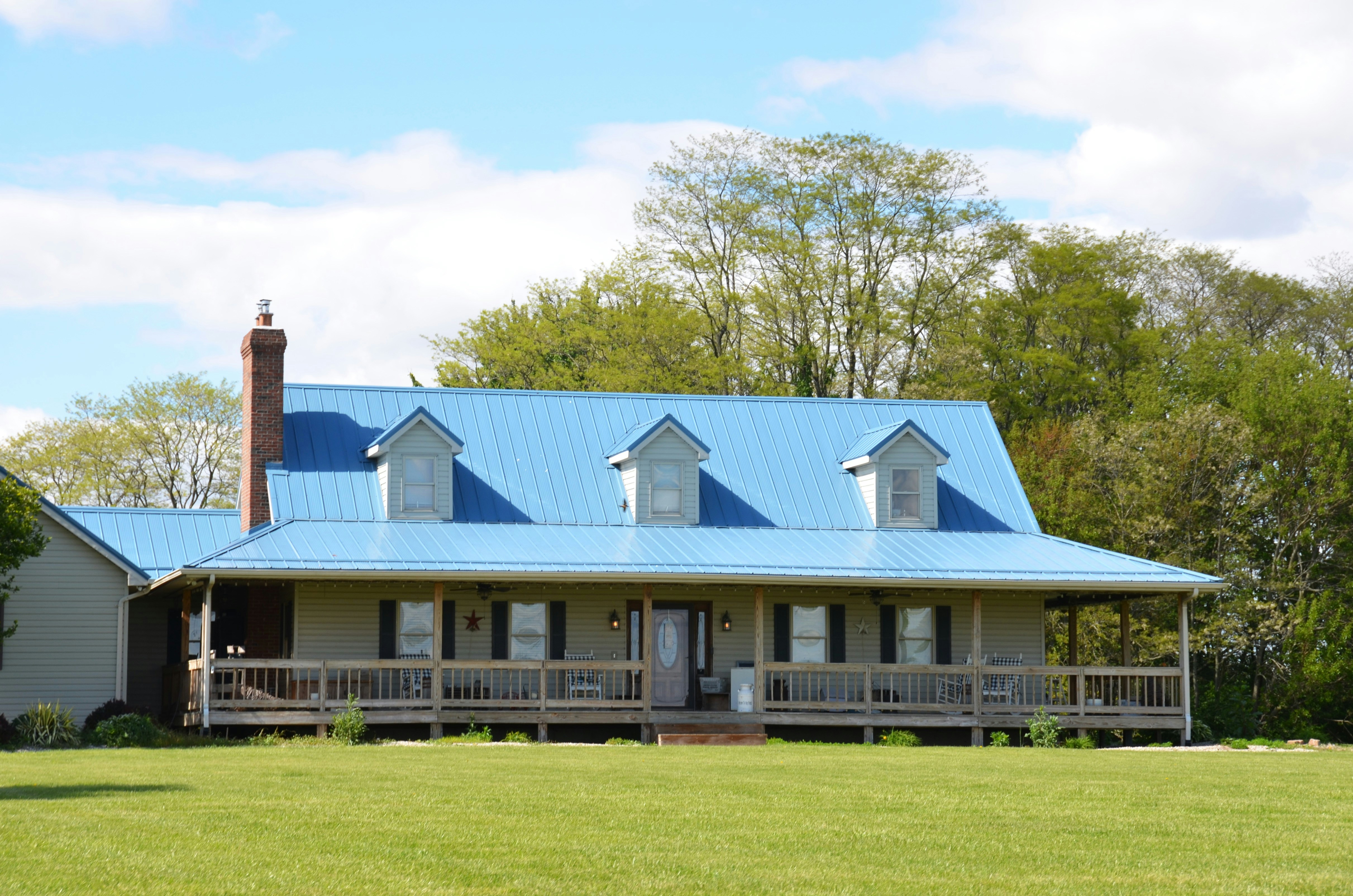 Una grande casa con tetto e veranda in metallo blu.