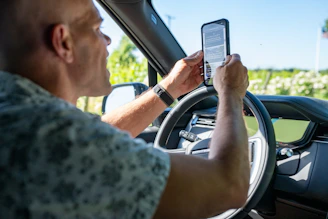 Man holding phone while driving a car