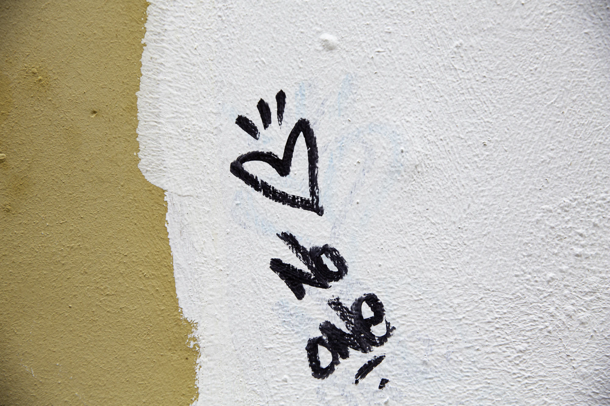Coração desenhado a caneta preta num muro branco com a palavra love. Foto: New York Said / Unsplash