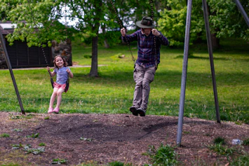 A man and a child swinging on playground swings