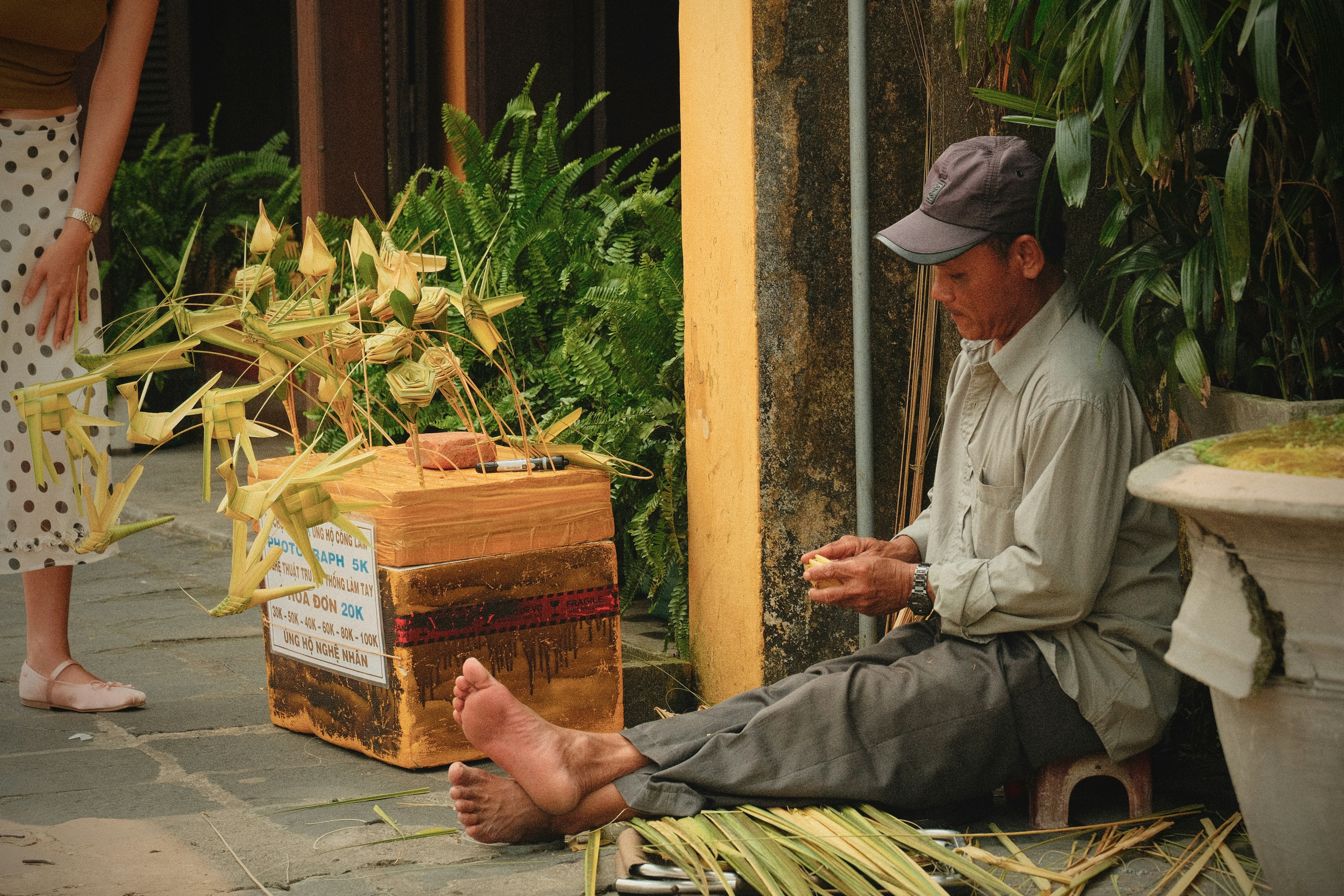 Un homme tissant des feuilles de palmier près d’une boîte