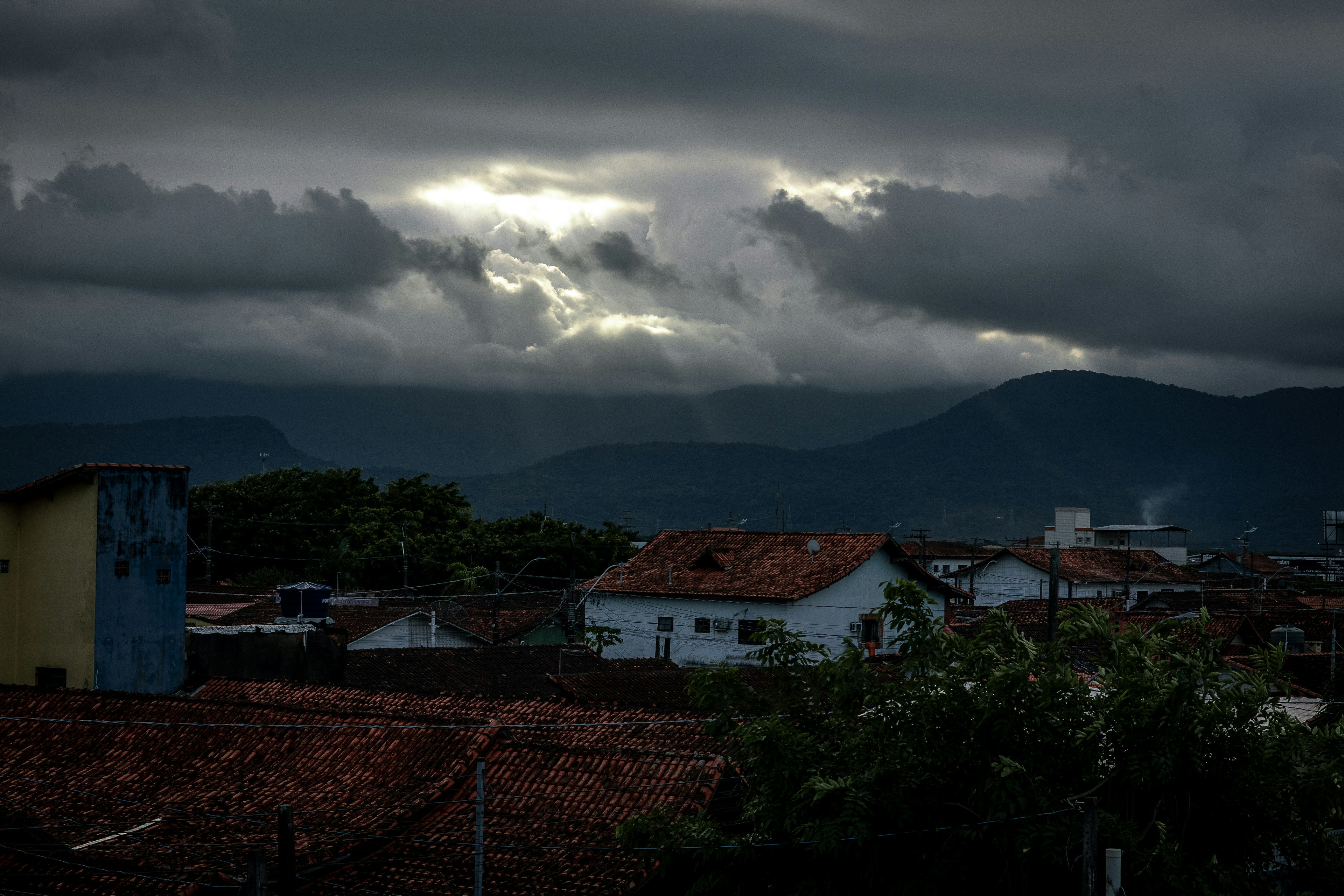 Sunlight breaks through stormy clouds over distant mountains.
