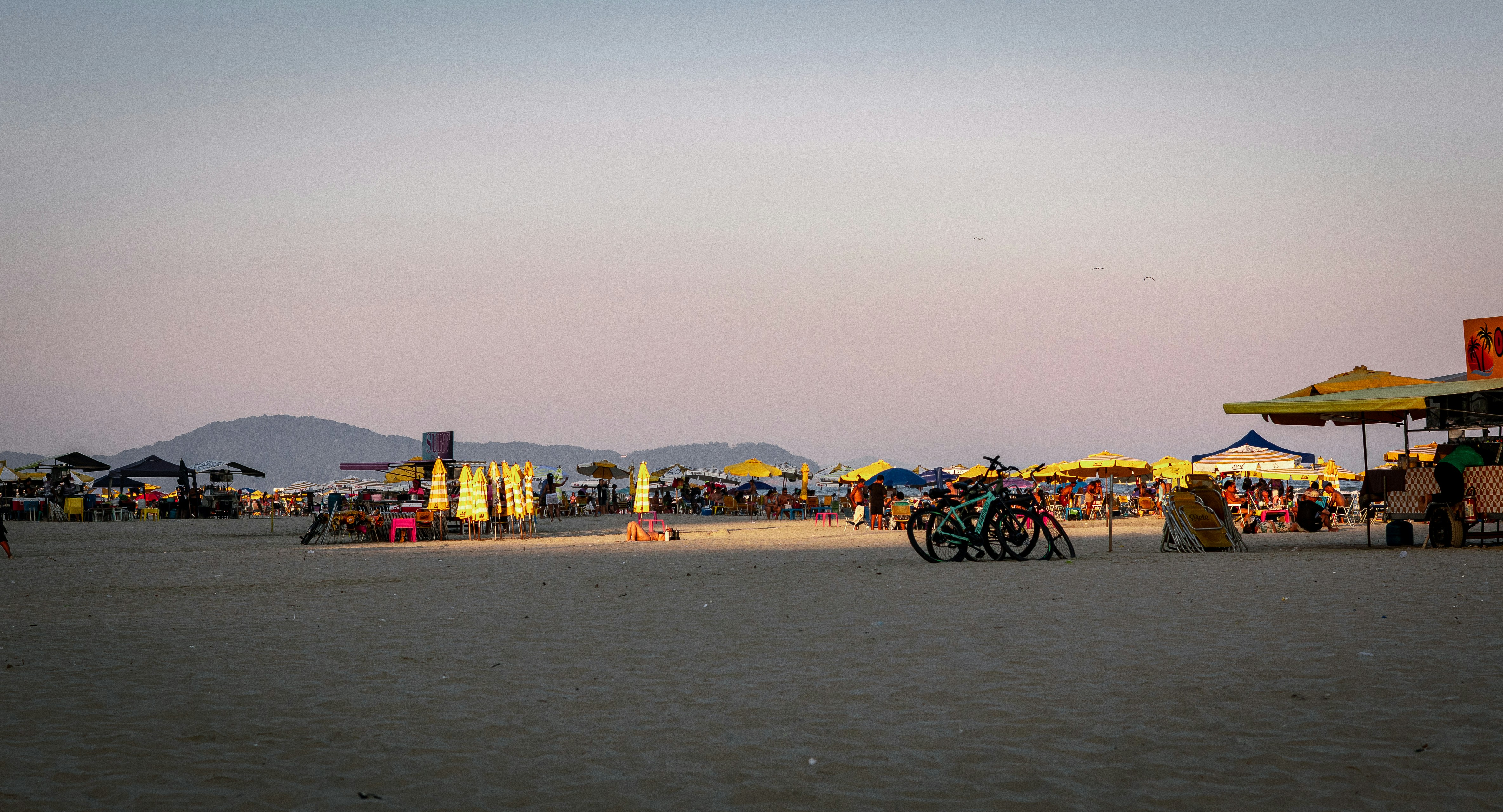 People enjoying a crowded beach with umbrellas and tents.