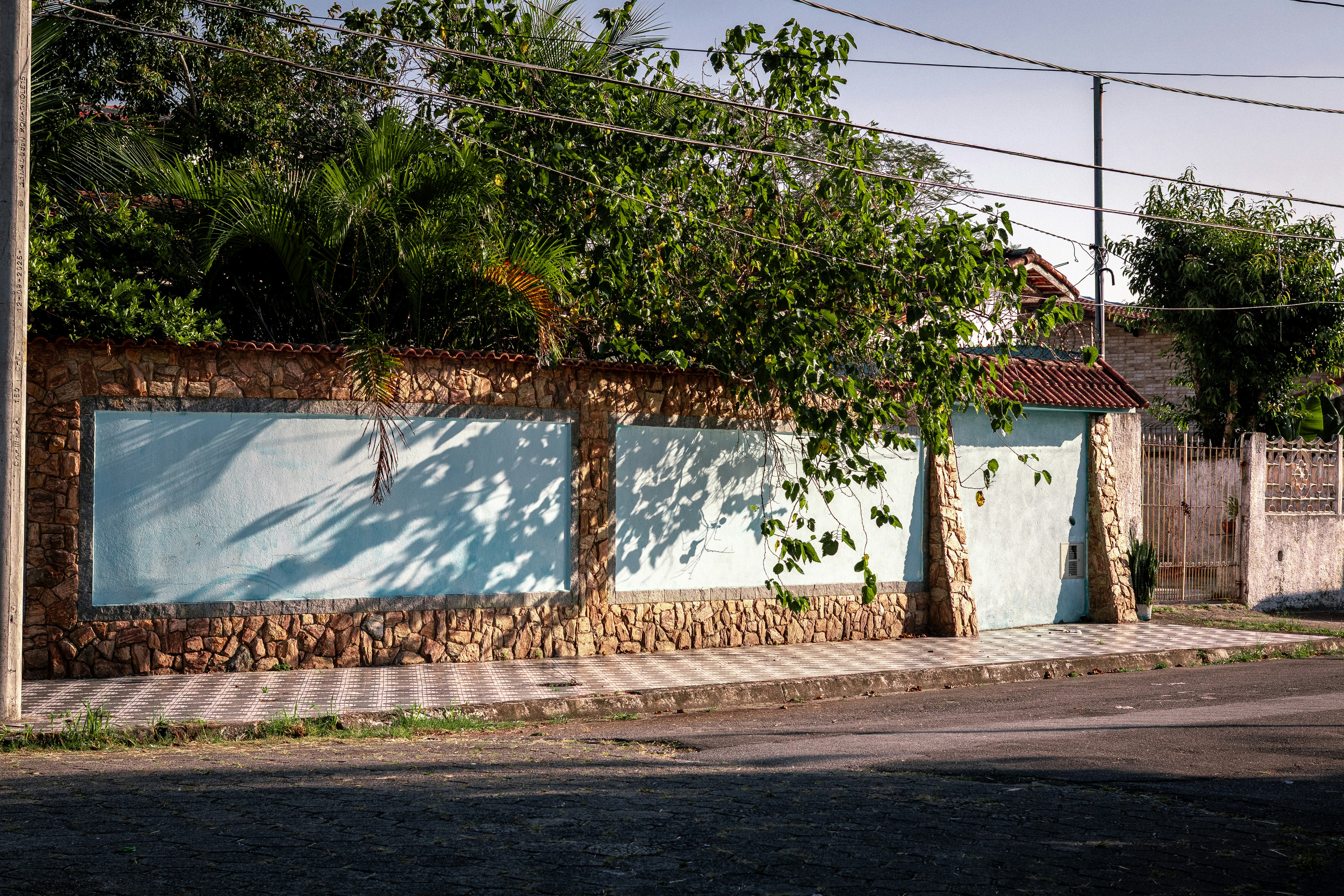 Stone wall with two large blue panels and trees.