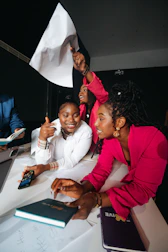 Three women celebrating and holding a white flag.