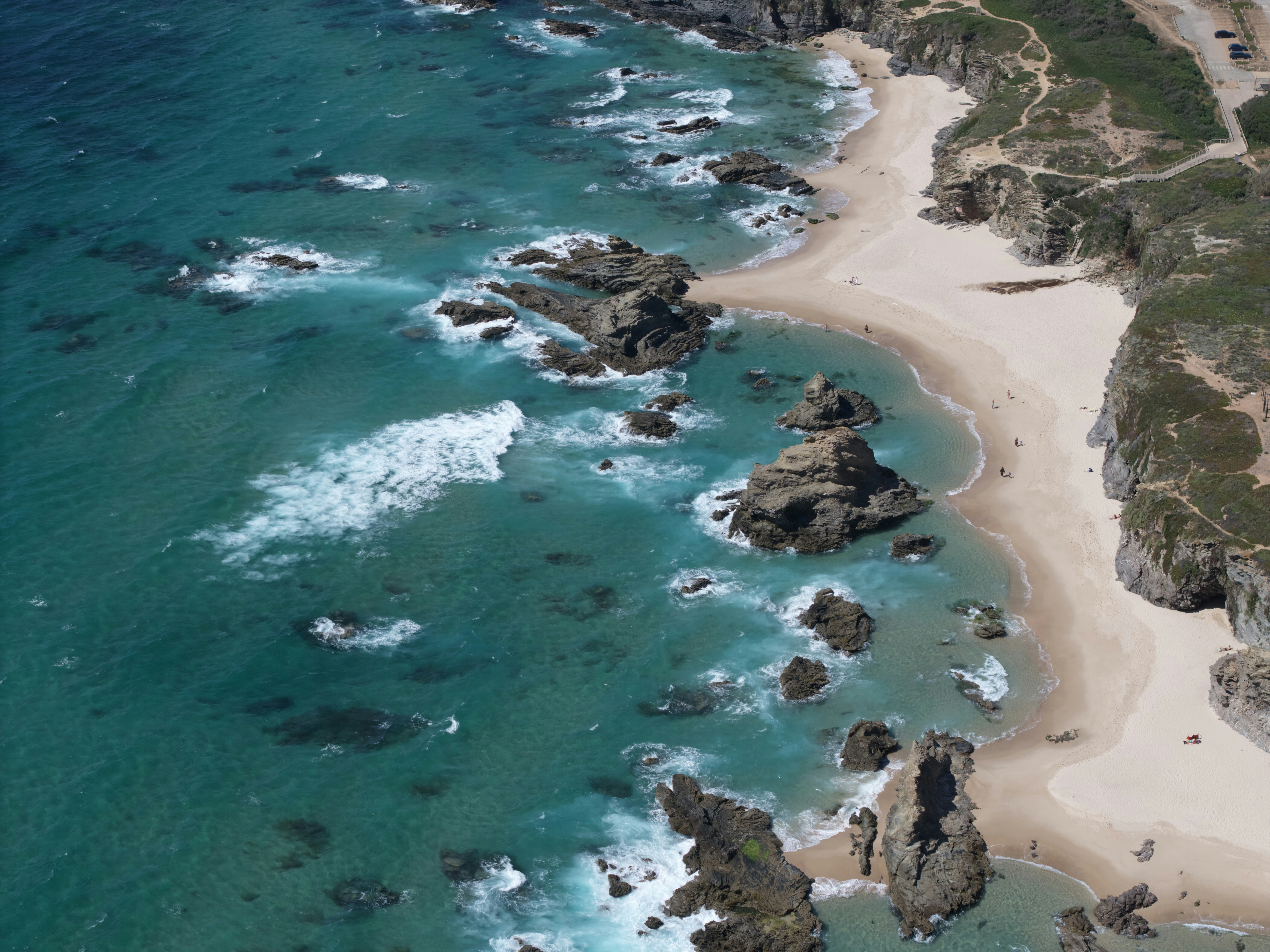 Turquoise ocean waves crash on a rocky coastline beach.