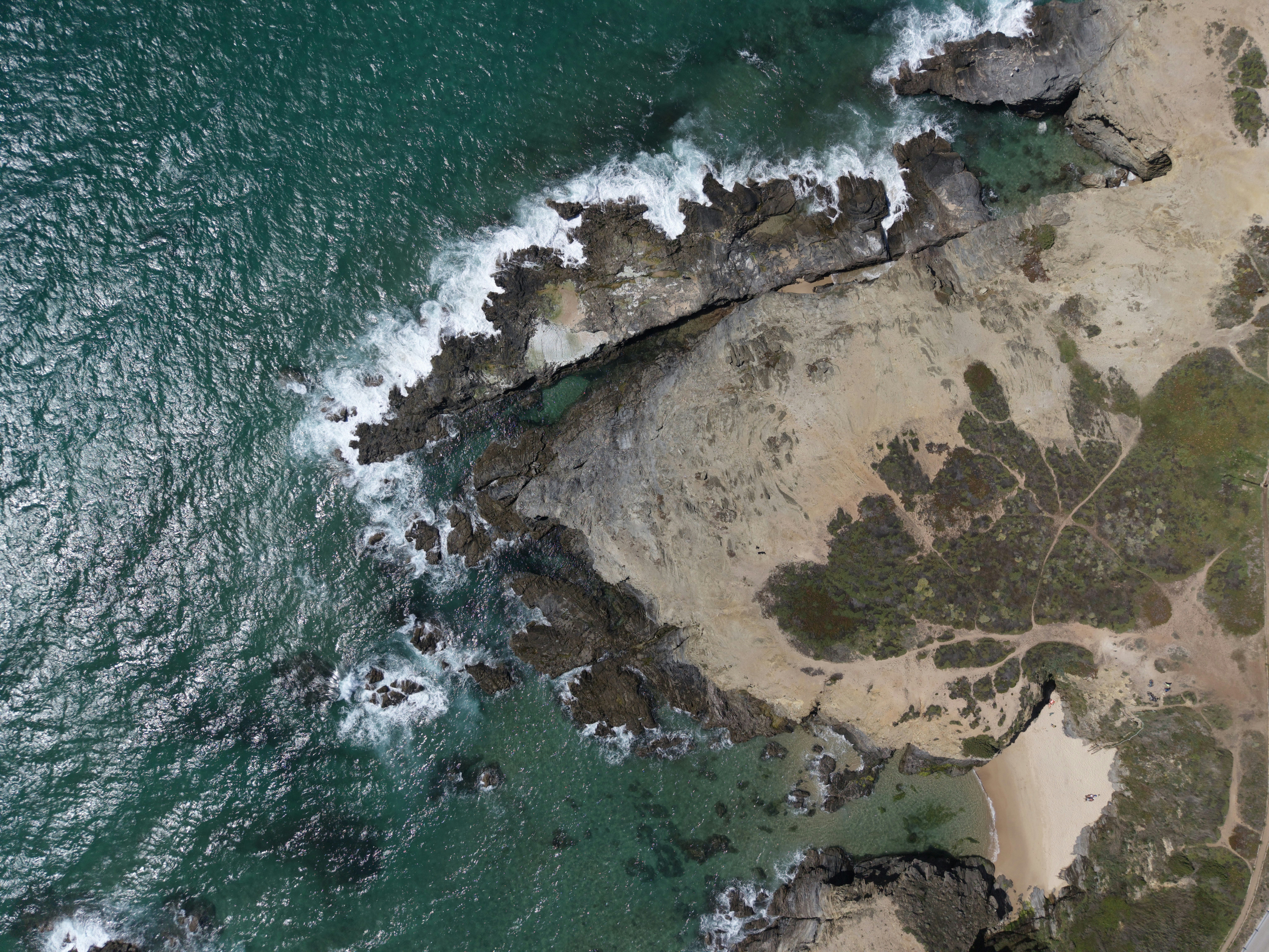Waves crash on rocky coastline with turquoise water.