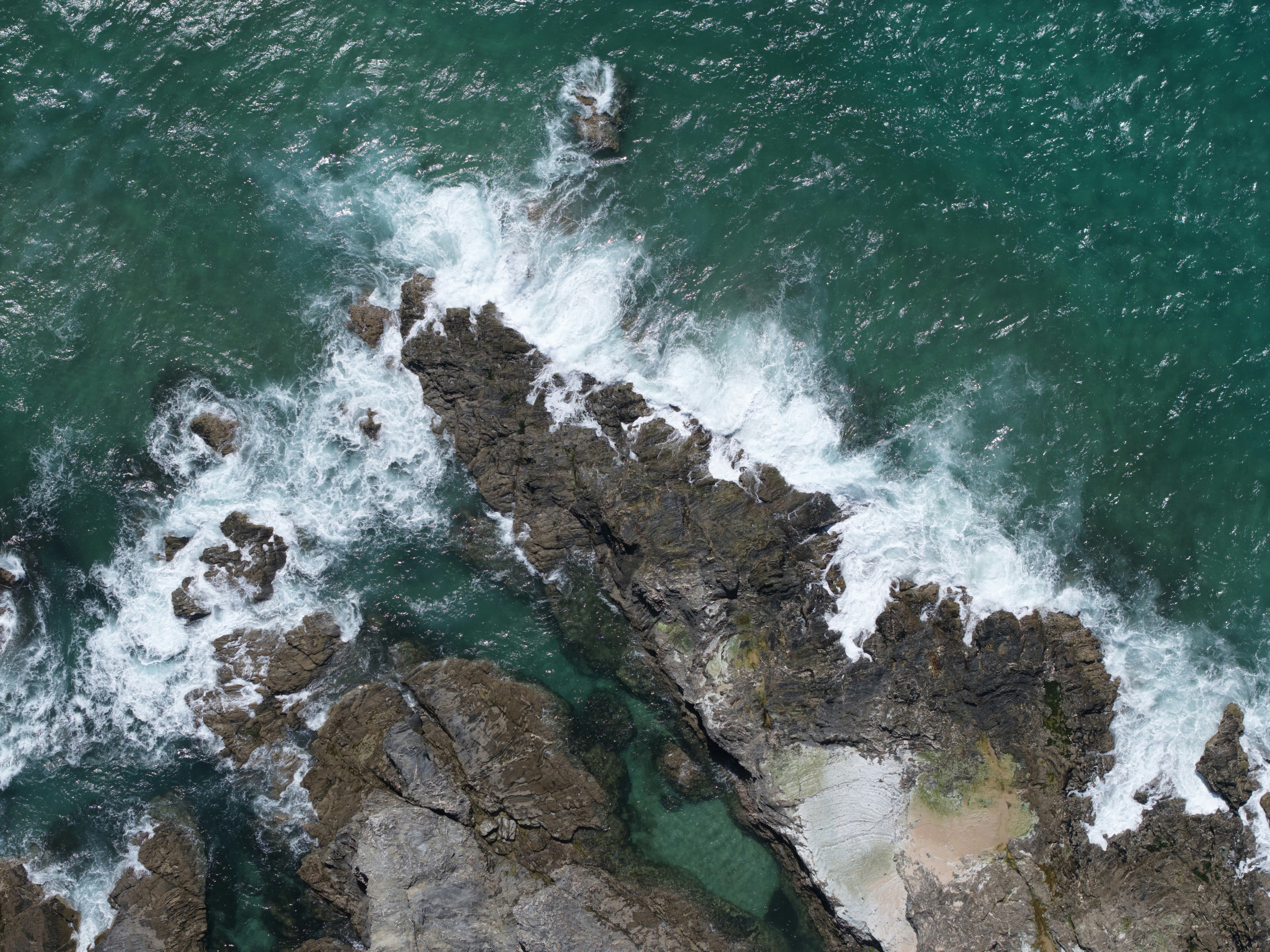 Waves crashing on rocky coastline with clear water