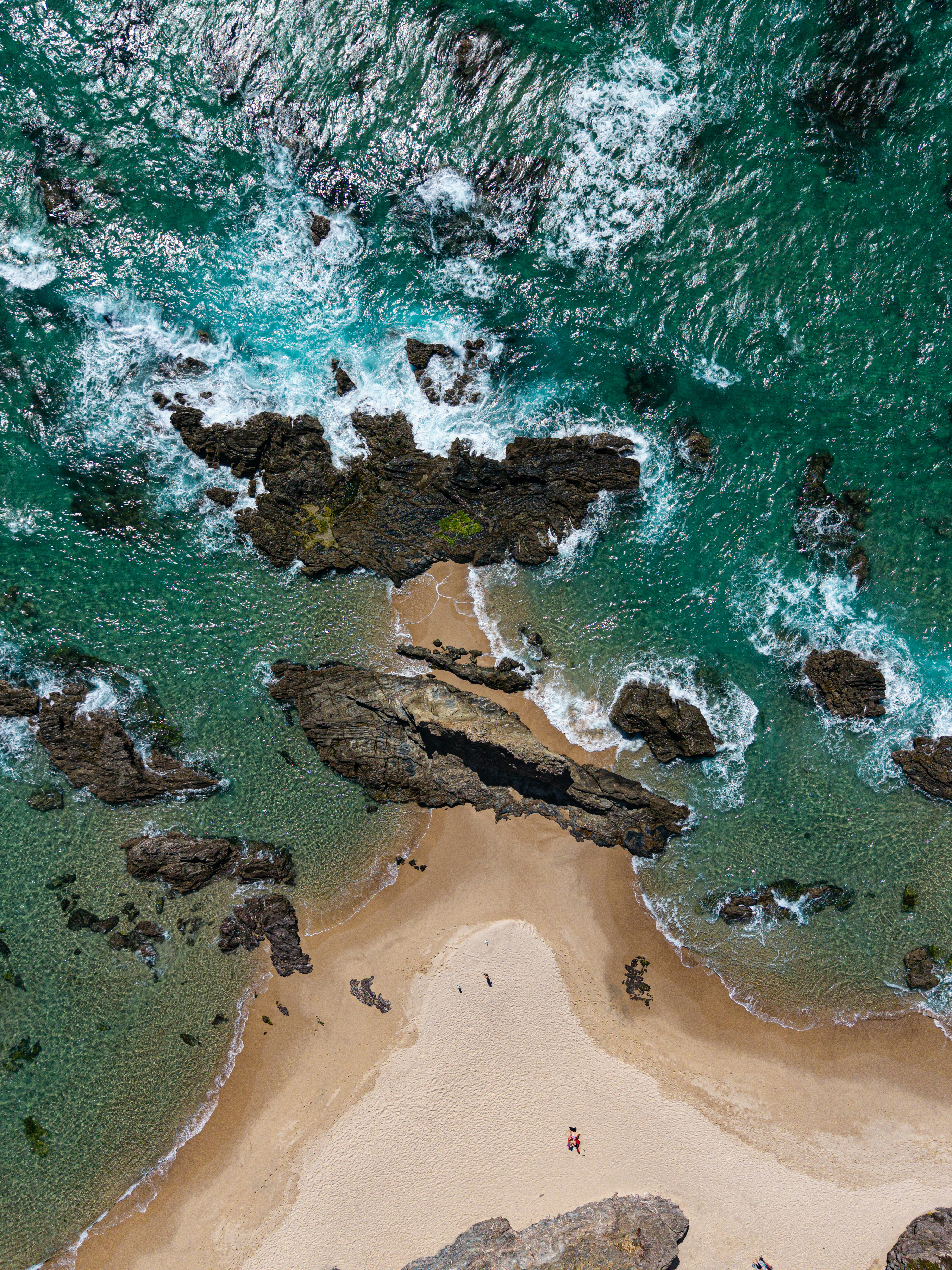 Aerial view of a sandy beach and rocky coastline.