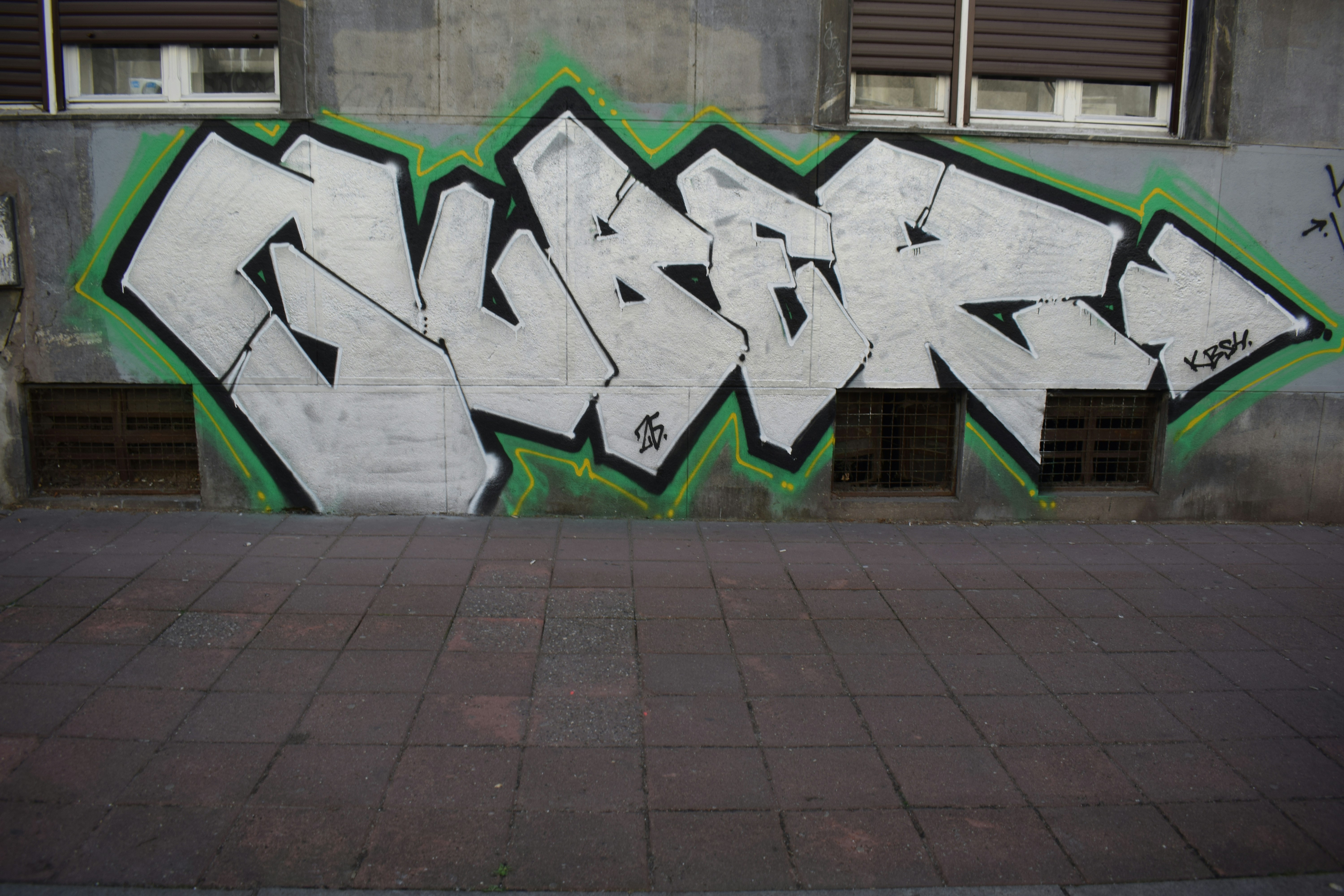 Un graffiti blanc avec un contour vert sur le mur.