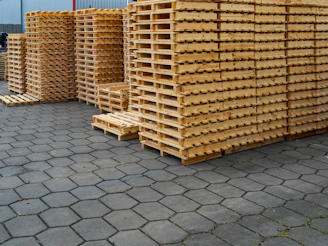 Stacks of wooden pallets on a paved surface.