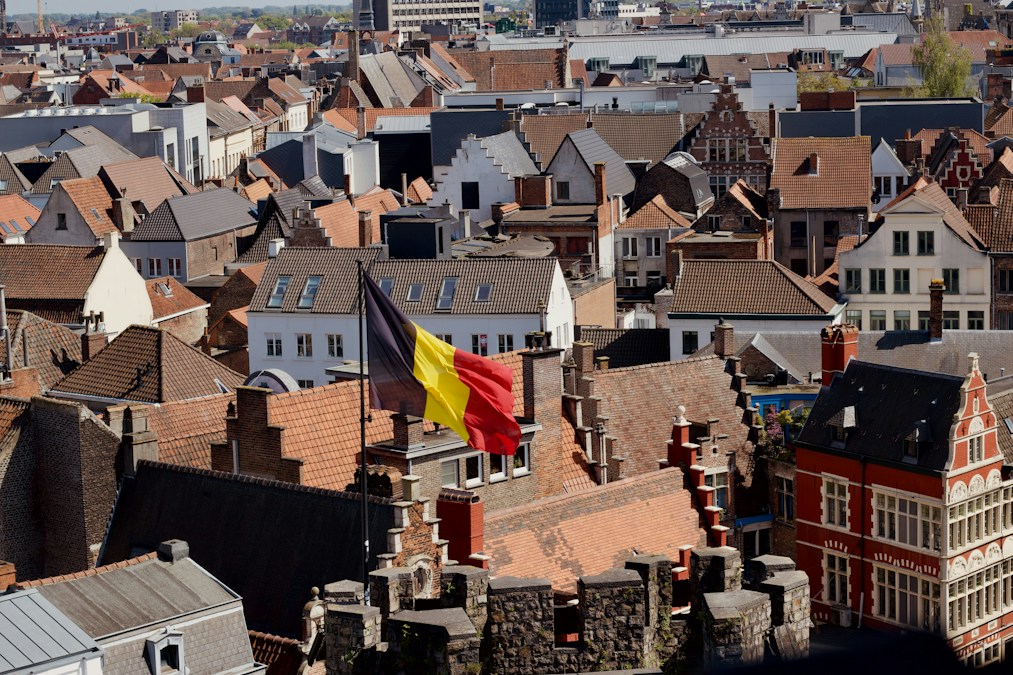 Drapeau belge flottant au-dessus des toits d’une ville flamande, illustration du calendrier des jours fériés en Belgique en 2026