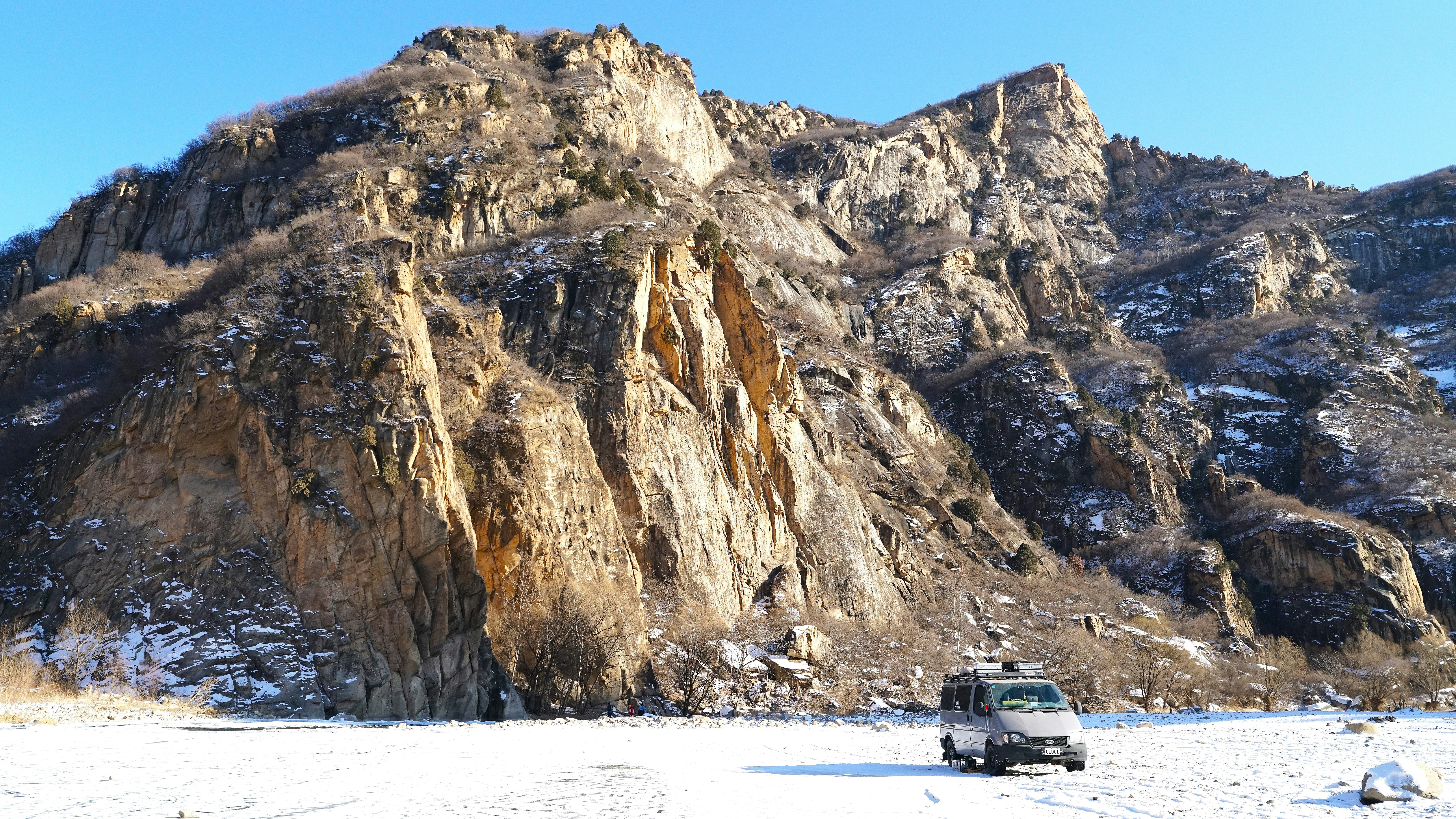A vehicle on snow with rugged, snow-dusted mountains