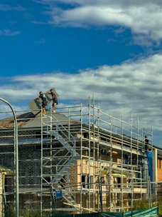 Workers installing solar panels on a house under construction.